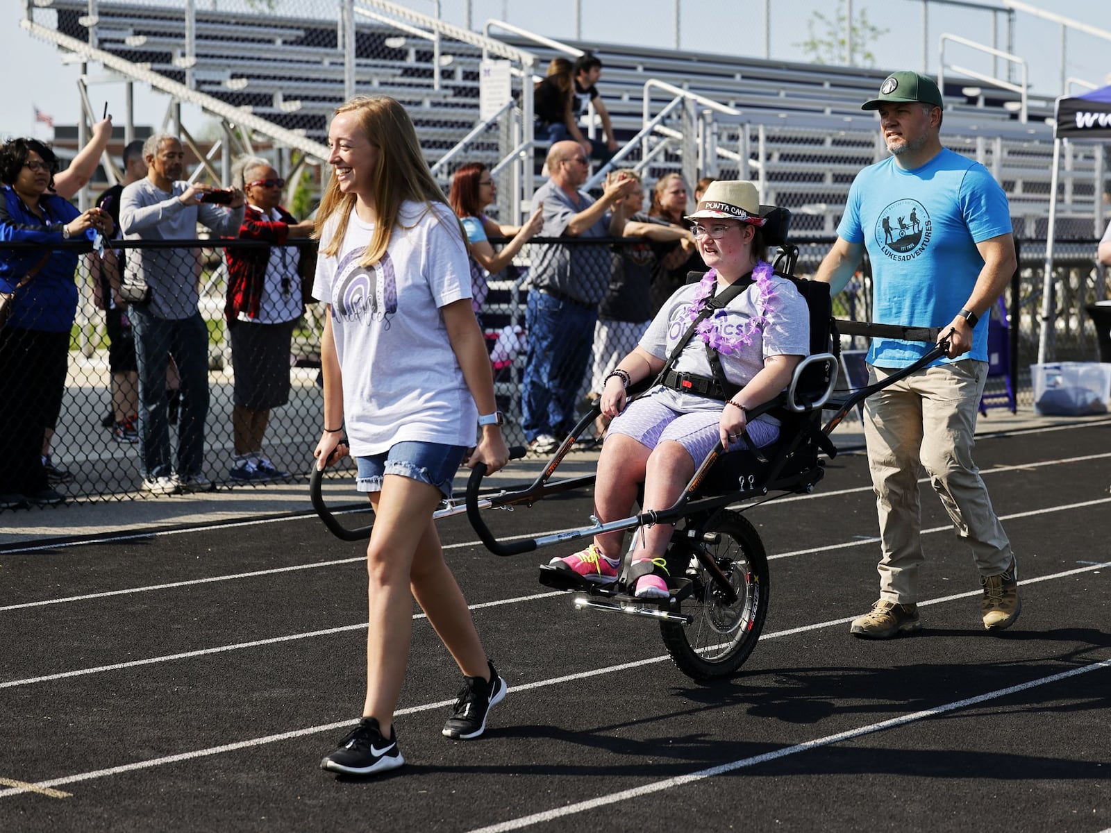 Ellwy Ferrell, middle, is helped around the track during the parade lap of Middie Olympics day Thursday, May 12, 2022 at Middletown High School. Community and student volunteers helped and students from all Middletown schools participated. NICK GRAHAM/STAFF