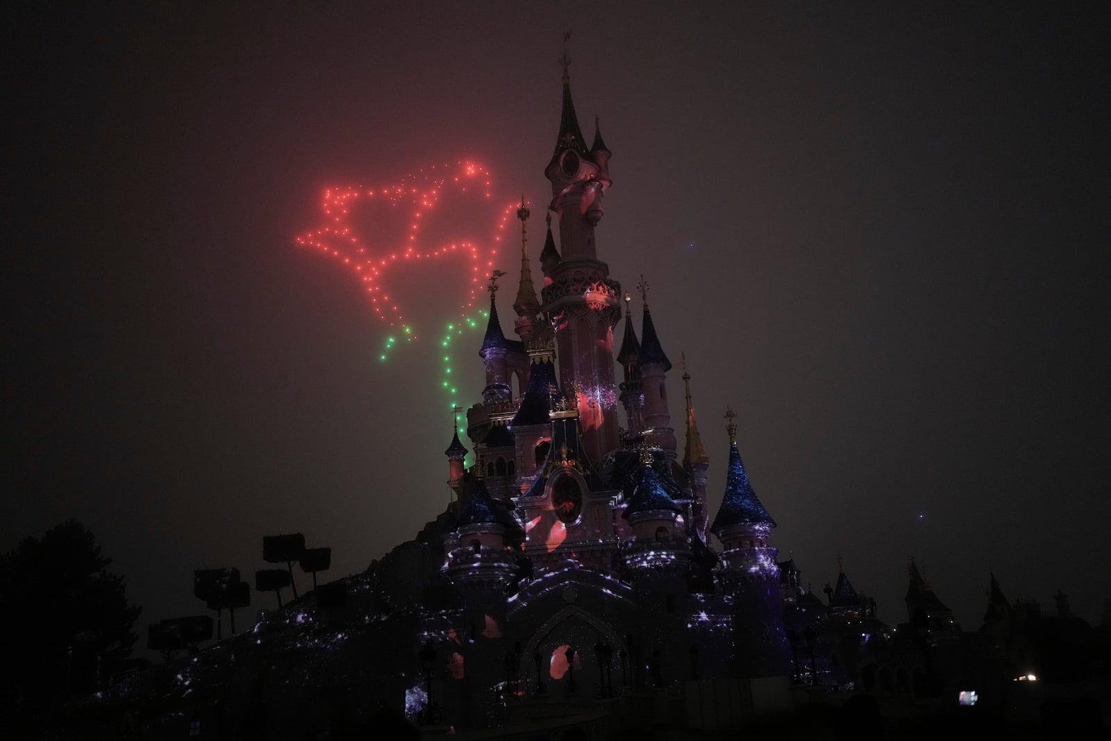 A light show is projected on the castle of Sleeping Beauty as fireworks explode in Disneyland, in Marne-la-Vallee, east of Paris, Friday Jan. 17, 2025. (AP Photo/Thibault Camus)