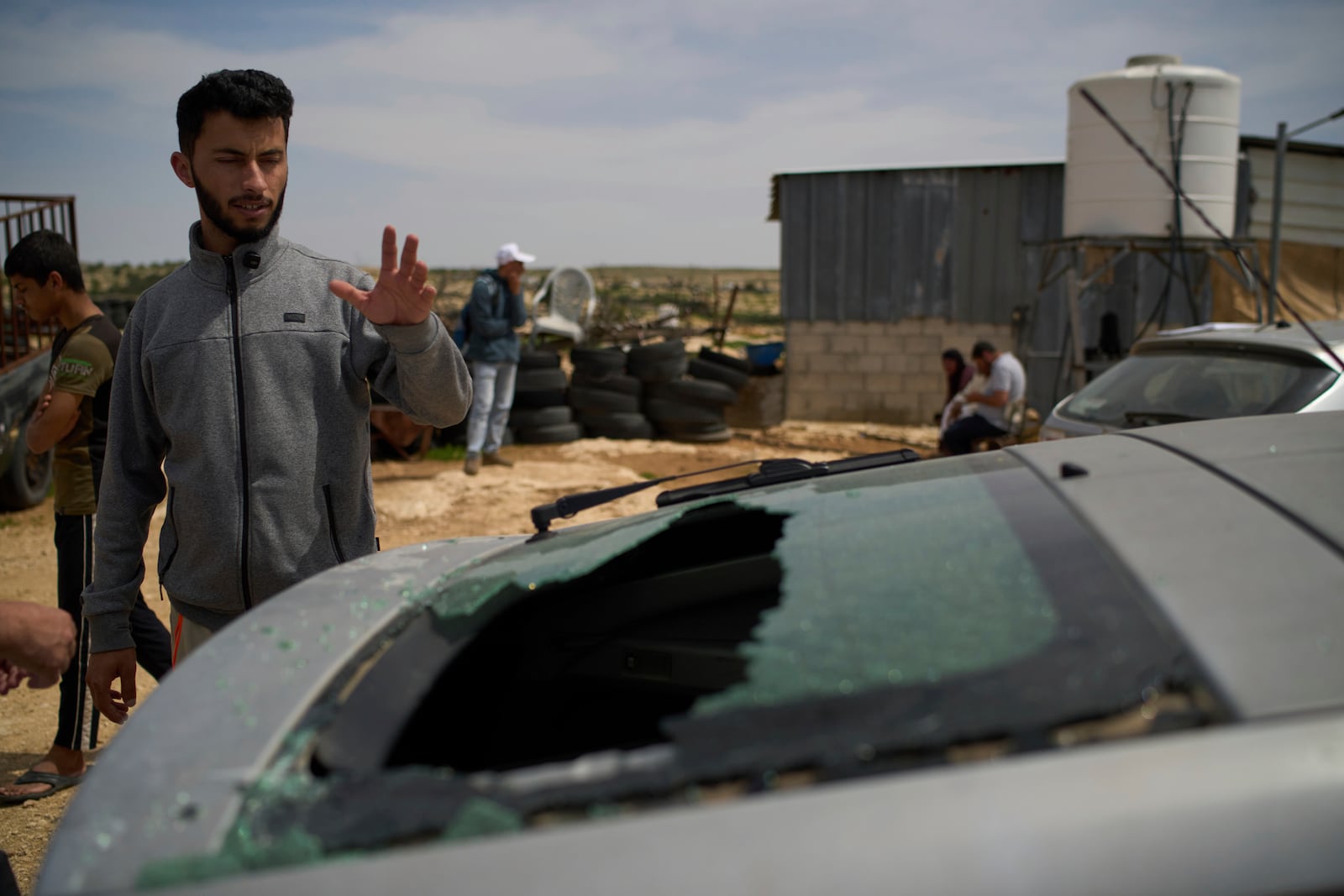 Basel Adra, Palestinian co-director of the Oscar winner documentary "No Other Land", looks at the damaged car of the Palestinian co-director Hamdan Ballal, who was attacked by Jewish settlers before being detained by the Israeli army in the village of Susiya, in Masafer Yatta, south Hebron hills, Tuesday, March 25, 2025. (AP Photo/Leo Correa)