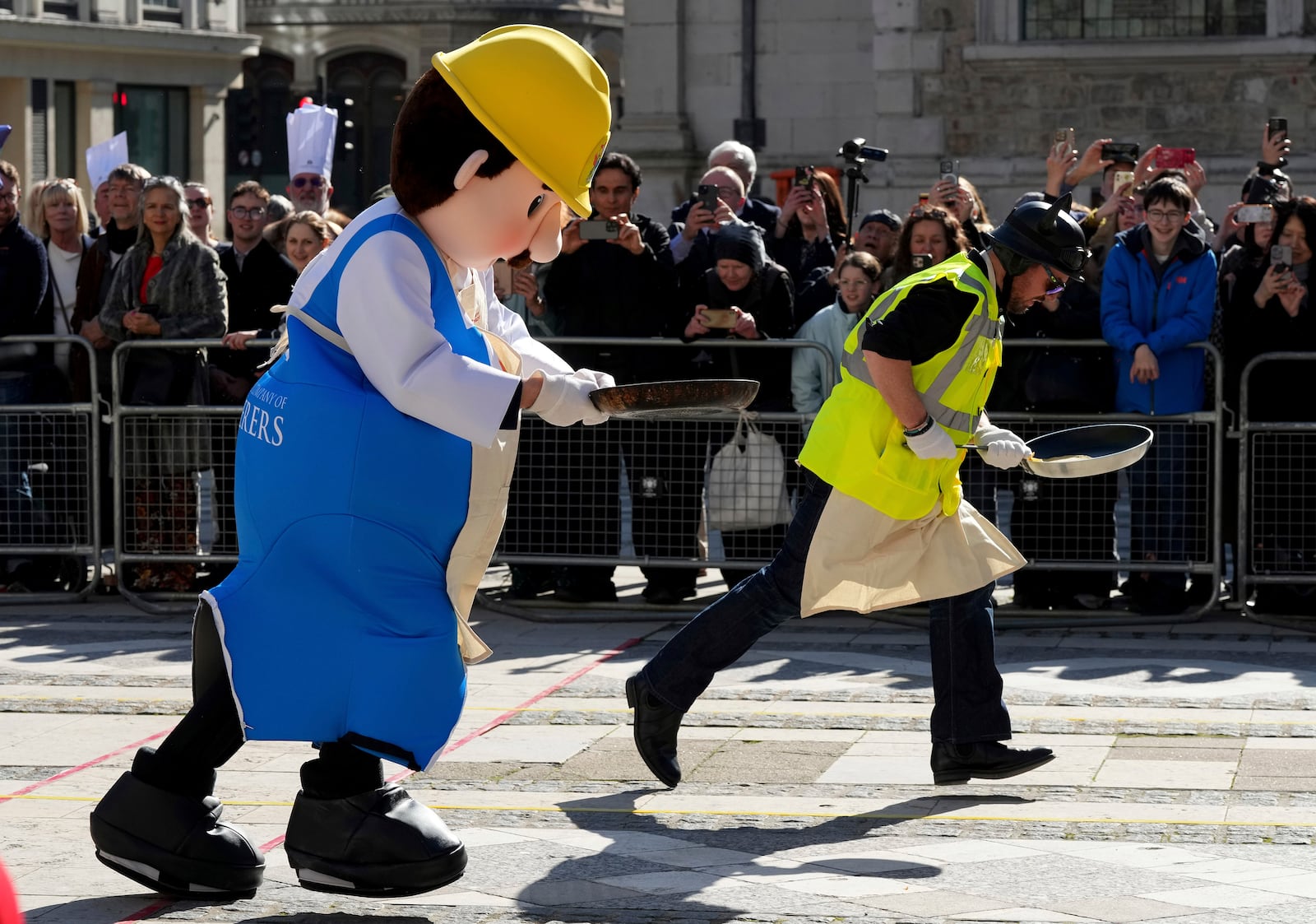 Runners in costumes compete during a traditional pancake race by livery companies at the Guildhall in London, Tuesday, March 4, 2025.(AP Photo/Frank Augstein)