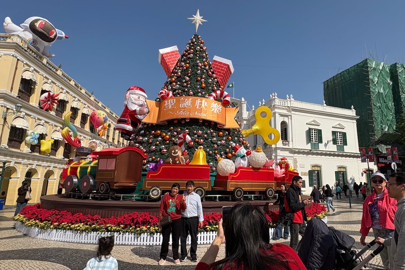 Mainland Chinese tourists take photos in front of a Christmas installation in Macao's historic Senado Square on Dec. 13, 2024. (AP Photo/Kanis Leung)