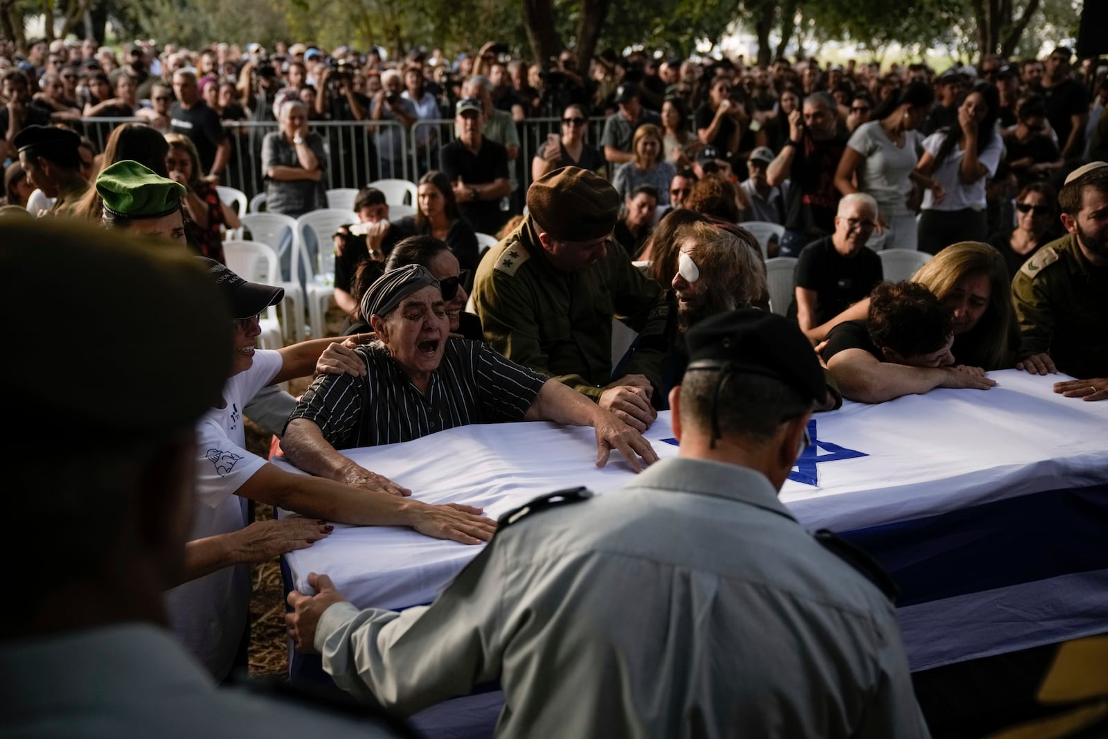 People mourn over the flagged-covered coffin of Israeli soldier Sgt. Amitai Alon, killed by a Hezbollah drone attack, during his funeral near Ramot Naftali, Israel, Monday, Oct. 14, 2024. (AP Photo/Leo Correa)