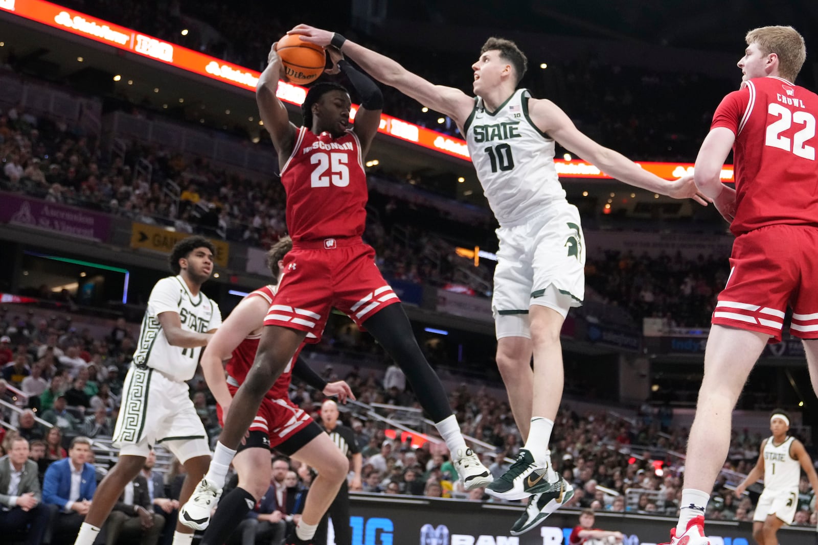 Wisconsin guard John Blackwell (25) pulls down a rebound on Michigan State center Szymon Zapala (10) as Steven Crowl (22) looks on during the first half of an NCAA college basketball game in the semifinals of the Big Ten Conference tournament in Indianapolis, Saturday, March 15, 2025. (AP Photo/Michael Conroy)