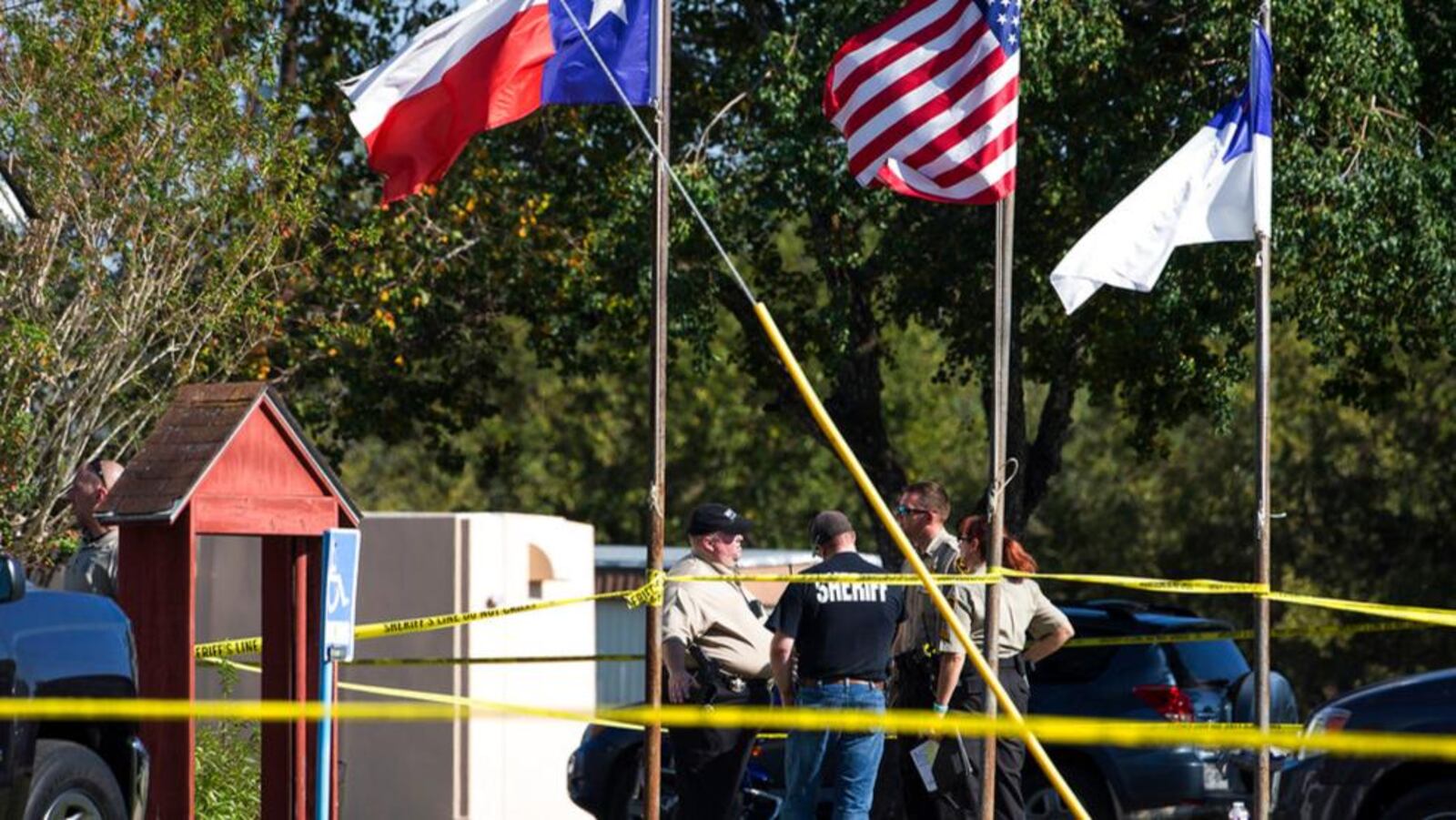 Law enforcement officials stand next to a covered body at the scene of a fatal shooting at the First Baptist Church in Sutherland Springs, Texas, on Sunday, Nov. 5, 2017. (Nick Wagner/Austin American-Statesman via AP)