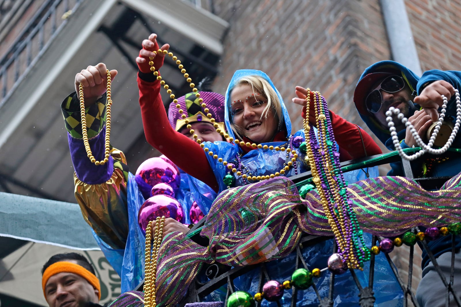 FILE - Revelers throw beads from balconies in the rain during Mardi Gras festivities in the French Quarter in New Orleans, March 4, 2014. AP Photo/Gerald Herbert, File)