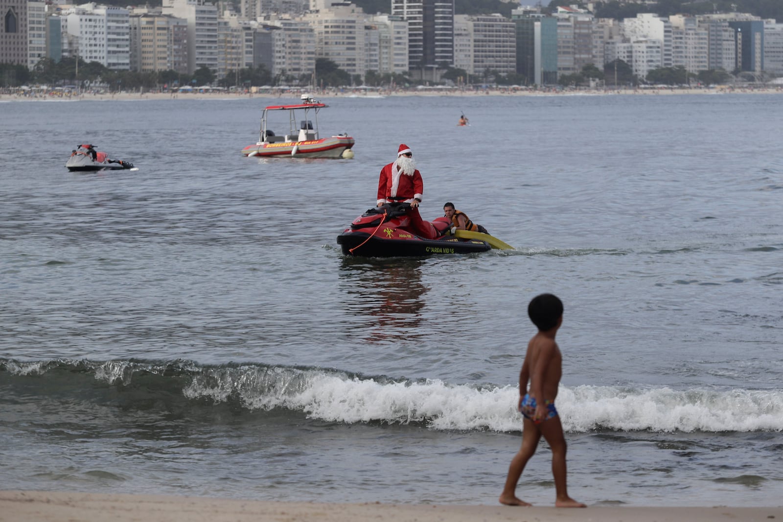 A firefighter dressed as Santa Claus rescues a man on Copacabana Beach in Rio de Janeiro, Tuesday, Dec. 17, 2024. (AP Photo/Bruna Prado)