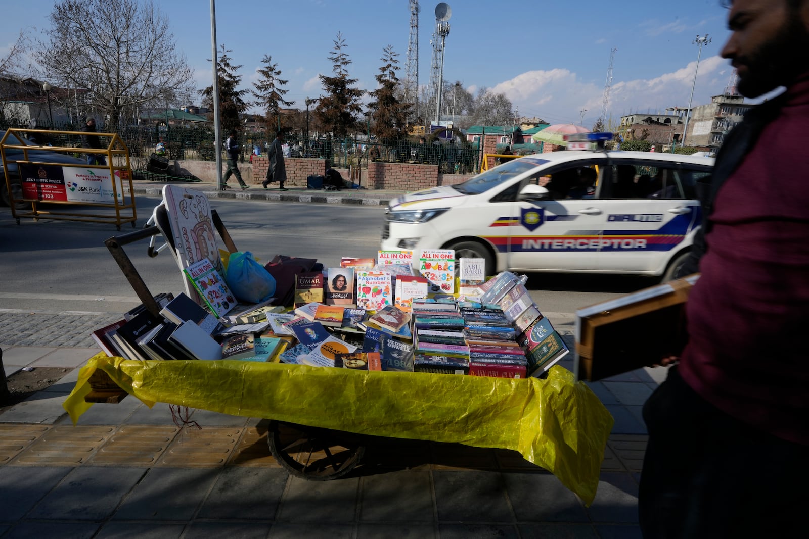 Books are displayed for sale on a handcart as a police vehicle patrols in Srinagar, Indian controlled Kashmir, Monday, Feb. 17, 2025. (AP Photo/Mukhtar Khan)