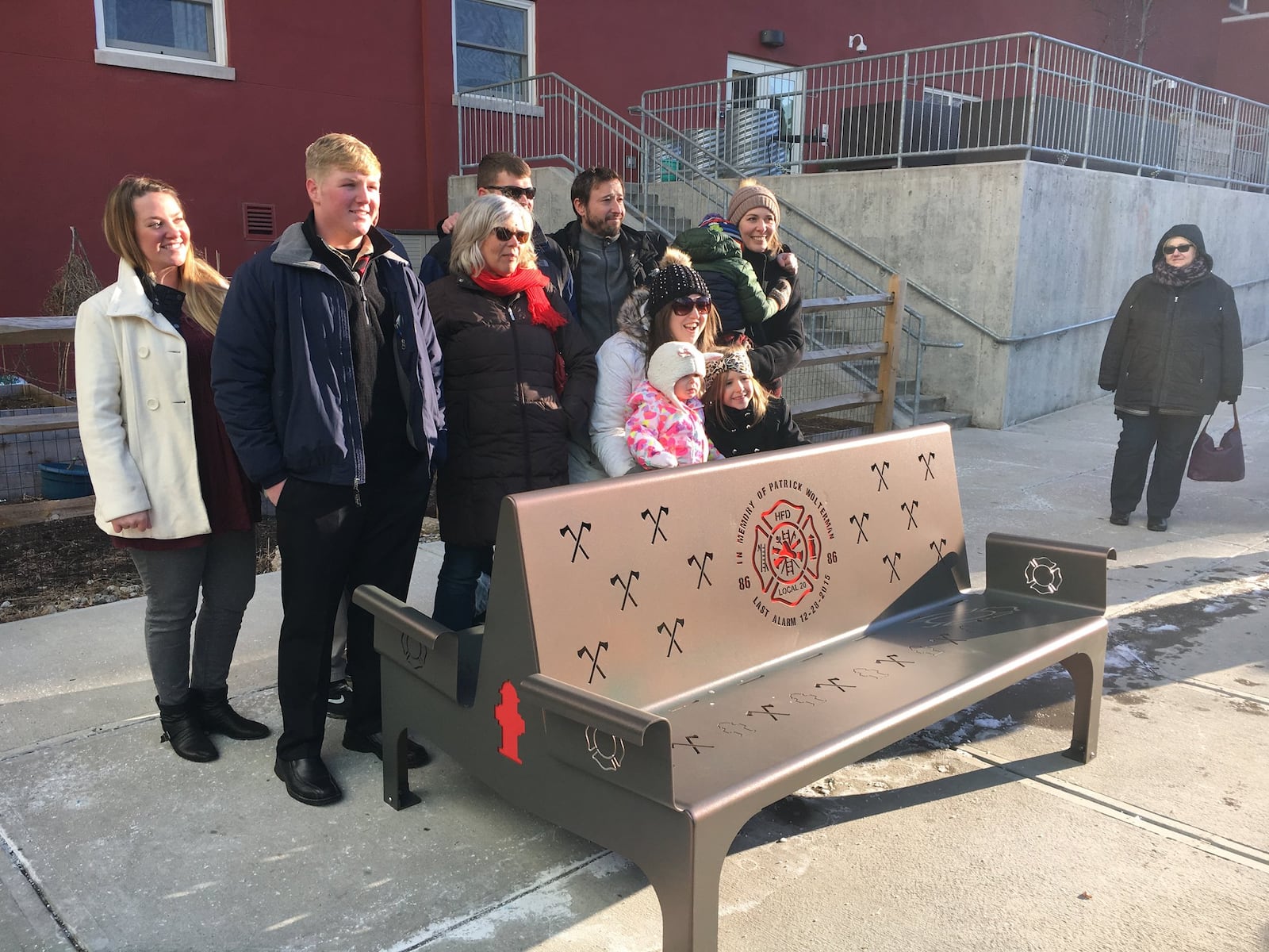 Boy Scout Daniel Nienaber, (front row left) was joined by members of fallen firefighter Patrick Wolterman’s family and friends along with several firefighters Thursday afternoon at Rotary Park in downtown Hamilton for the dedication of a bench built by the scout in honor of the man who lost his life in the line of duty.