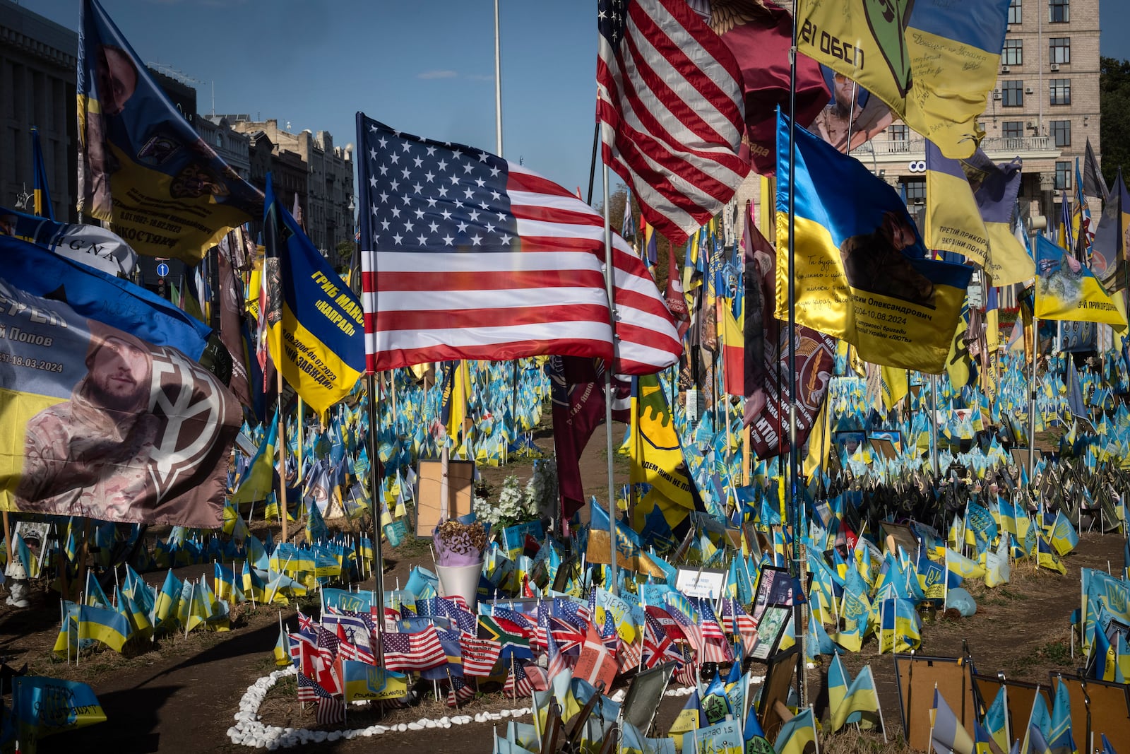 US and Ukrainian national flags wave to commemorate American volunteers, who were killed in battles with Russian troops defending Ukraine, their names are on flags, at the improvised war memorial in Independence square in Kyiv, Ukraine, Friday, Sept. 27, 2024. (AP Photo/Efrem Lukatsky)