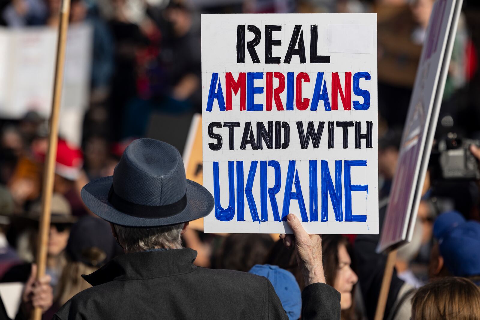 A demonstrator holds a poster reading, "Real Americans Stand with Ukraine," during a rally to protest President Donald Trump's policies on Presidents Day, Monday, Feb. 17, 2025, in Los Angeles. (AP Photo/Etienne Laurent)