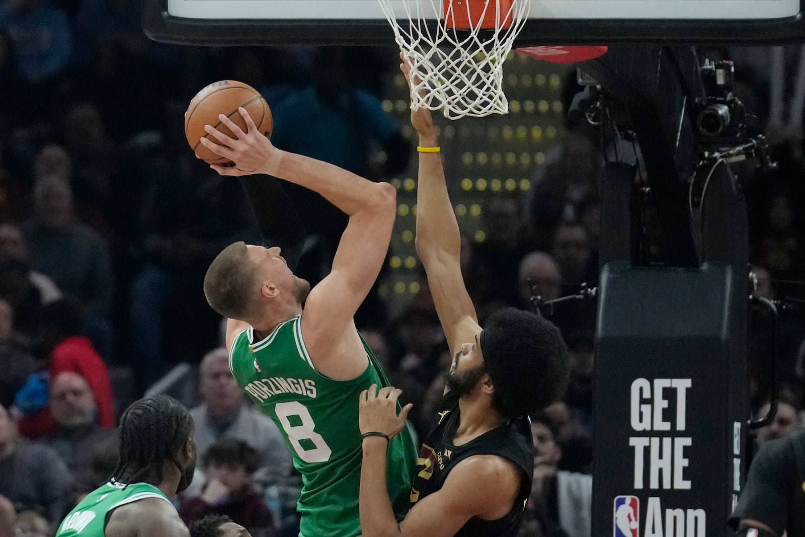 Boston Celtics center Kristaps Porzingis (8) shoots as Cleveland Cavaliers center Jarrett Allen, right, defends in the first half of an NBA basketball game, Tuesday, Feb. 4, 2025, in Cleveland. (AP Photo/Sue Ogrocki)