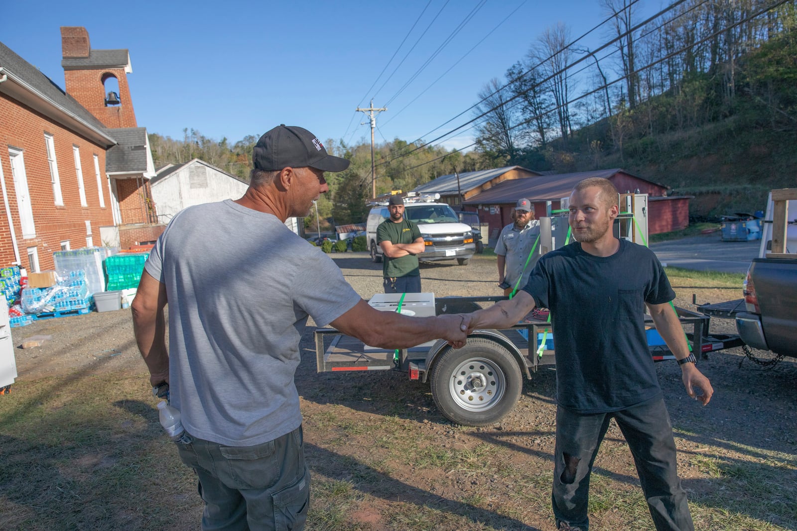 Bobby Renfro, left, thanks Footprint Project volunteer Henry Kovacs, right, after Kovacs helped install solar panels and a battery at a community building in Tipton Hill, N.C. on Oct. 9, 2024. (AP Photo/Gabriela Aoun Angueria)