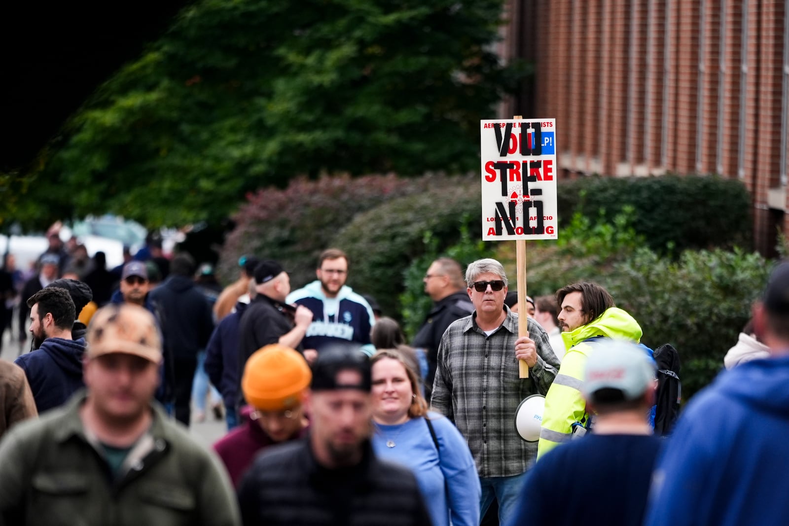 A worker holds a picket sign as Boeing employees vote on a new contract offer from the company, Wednesday, Oct. 23, 2024, at a voting location in the Angel of the Winds Arena in Everett, Wash. (AP Photo/Lindsey Wasson)