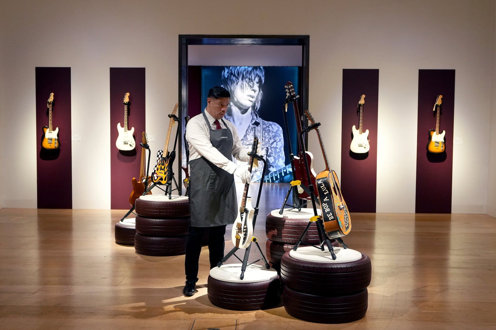 An art handler places guitars ahead of a pre-sale exhibition at Christie's auction rooms in London, Tuesday, Jan. 14, 2025. (AP Photo/Kirsty Wigglesworth)