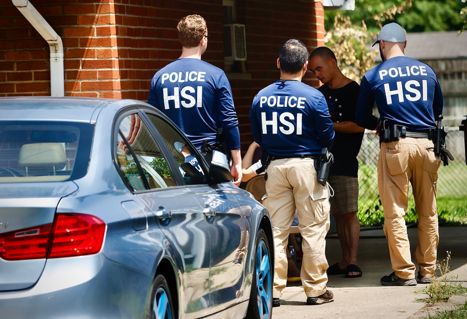 Homeland Security police talk to several people outside a home Friday, July 26, 2024 on Hoyle Pl. in Kettering. MARSHALL GORBY \STAFF