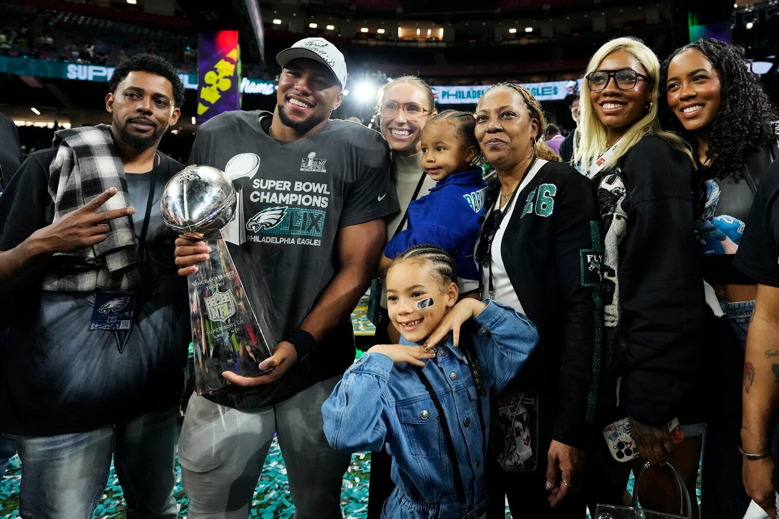 Philadelphia Eagles running back Saquon Barkley holds the Vince Lombardi Trophy with his family while posing for a photographer after the NFL Super Bowl 59 football game against the Kansas City Chiefs, Sunday, Feb. 9, 2025, in New Orleans. (AP Photo/Ashley Landis)