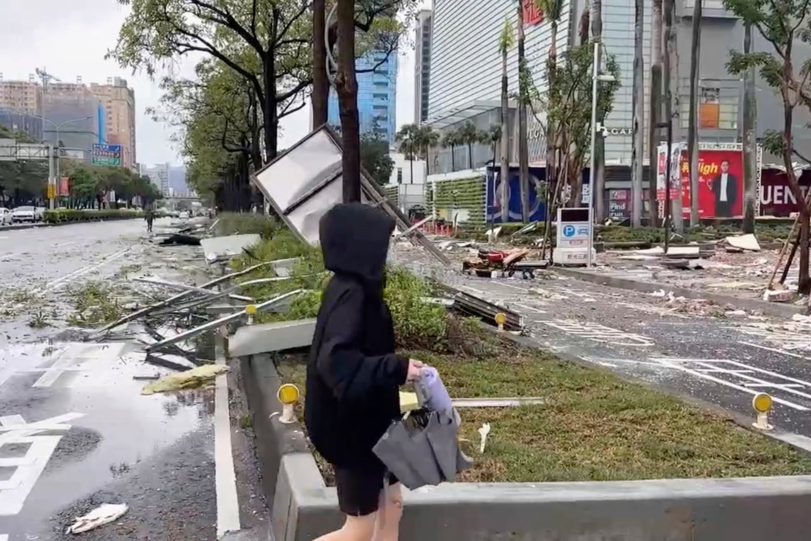 This image taken from video by Taiwan's TVBS shows that a person walks past debris from an explosion at the Shin Kong Mitsukoshi department store in Taichung city in Taiwan on Thursday, Feb. 13, 2025. (TVBS via AP )