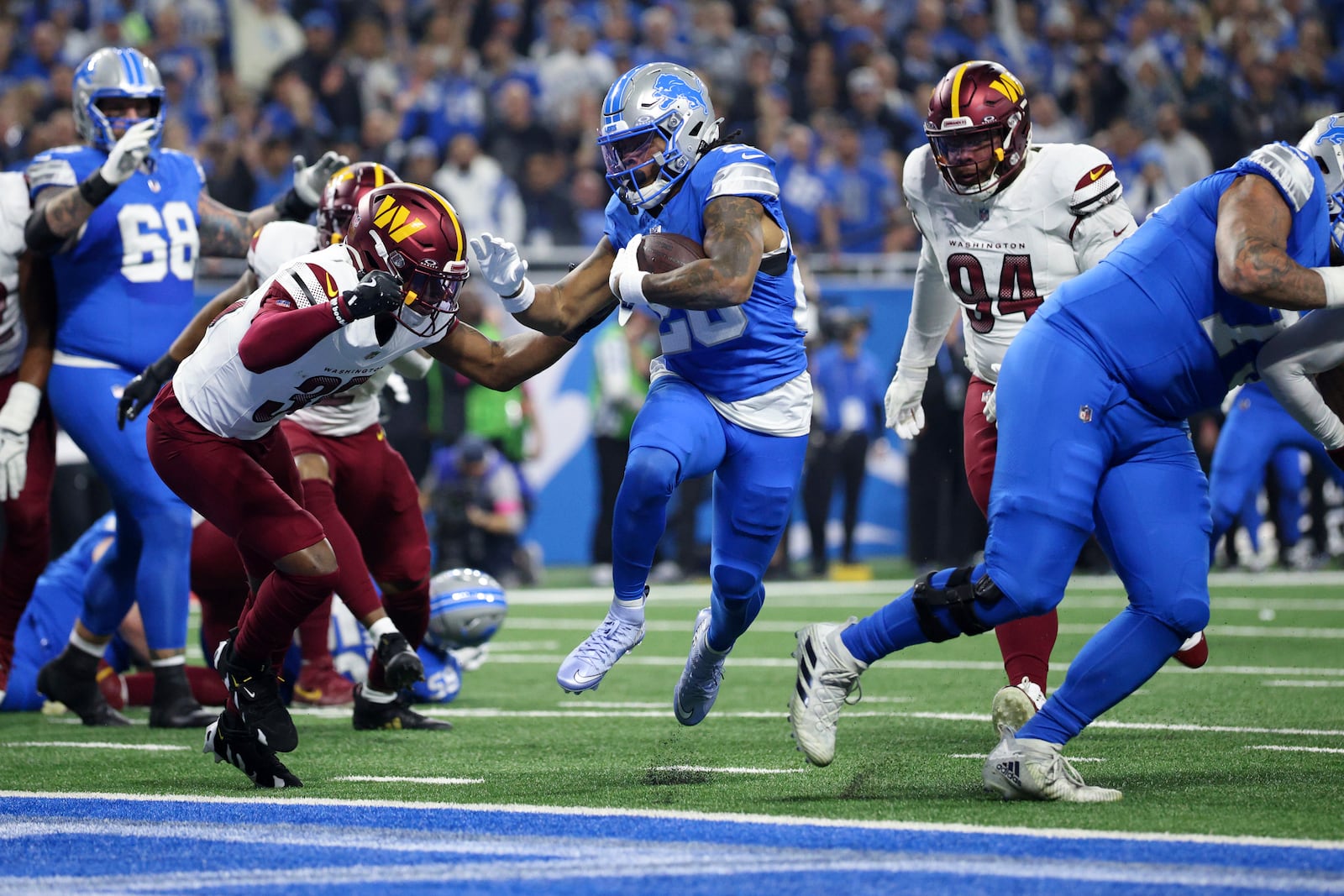 Detroit Lions running back Jahmyr Gibbs (26) runs for a one-yard touchdown run against the Washington Commanders during the first half of an NFL football divisional playoff game, Saturday, Jan. 18, 2025, in Detroit. (AP Photo/Mike Mulholland)