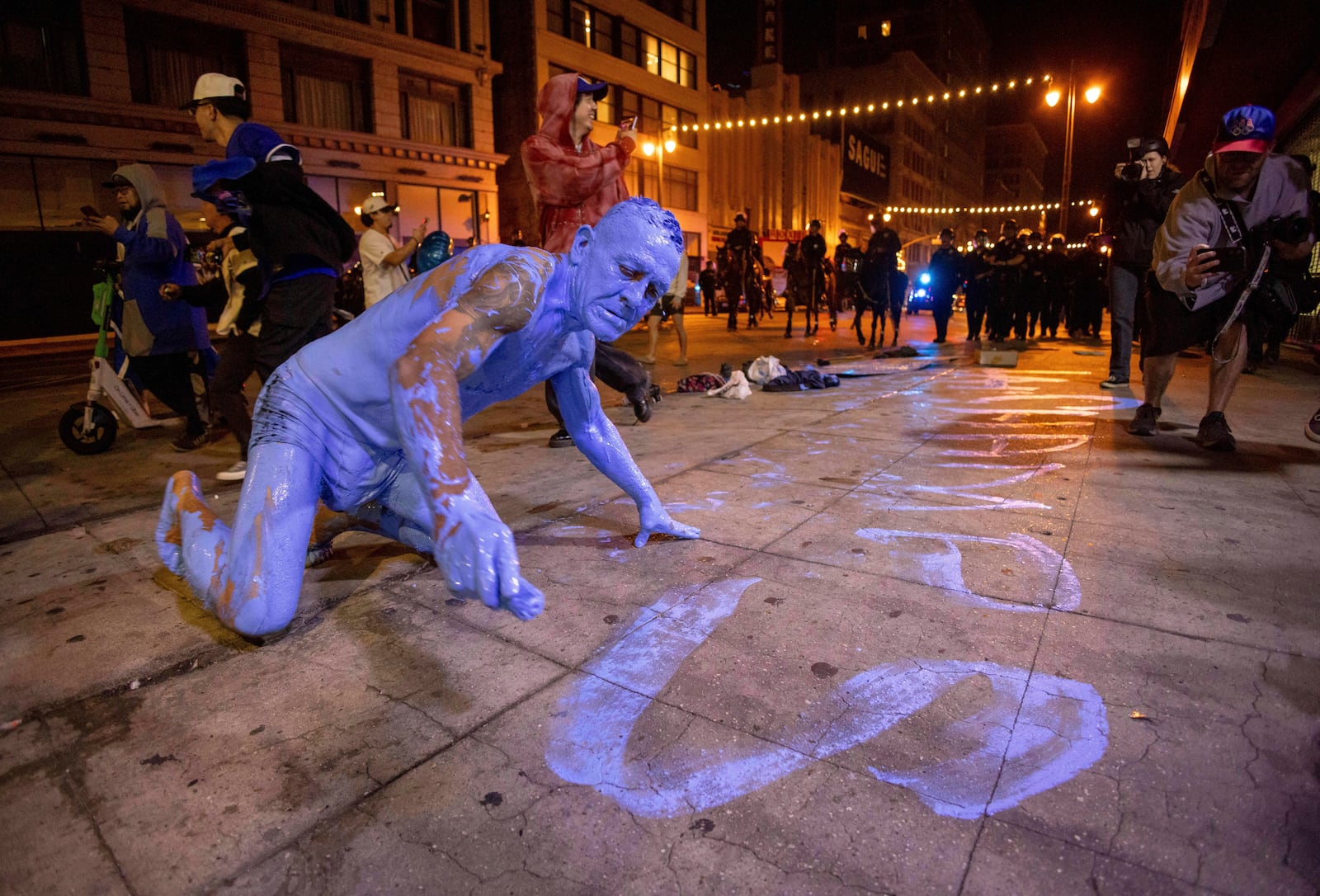 A person covered in blue paint, paints on the streets after the Los Angeles Dodgers won against the New York Yankees in the baseball World Series Wednesday, Oct. 30, 2024, in Los Angeles. (AP Photo/Ethan Swope)