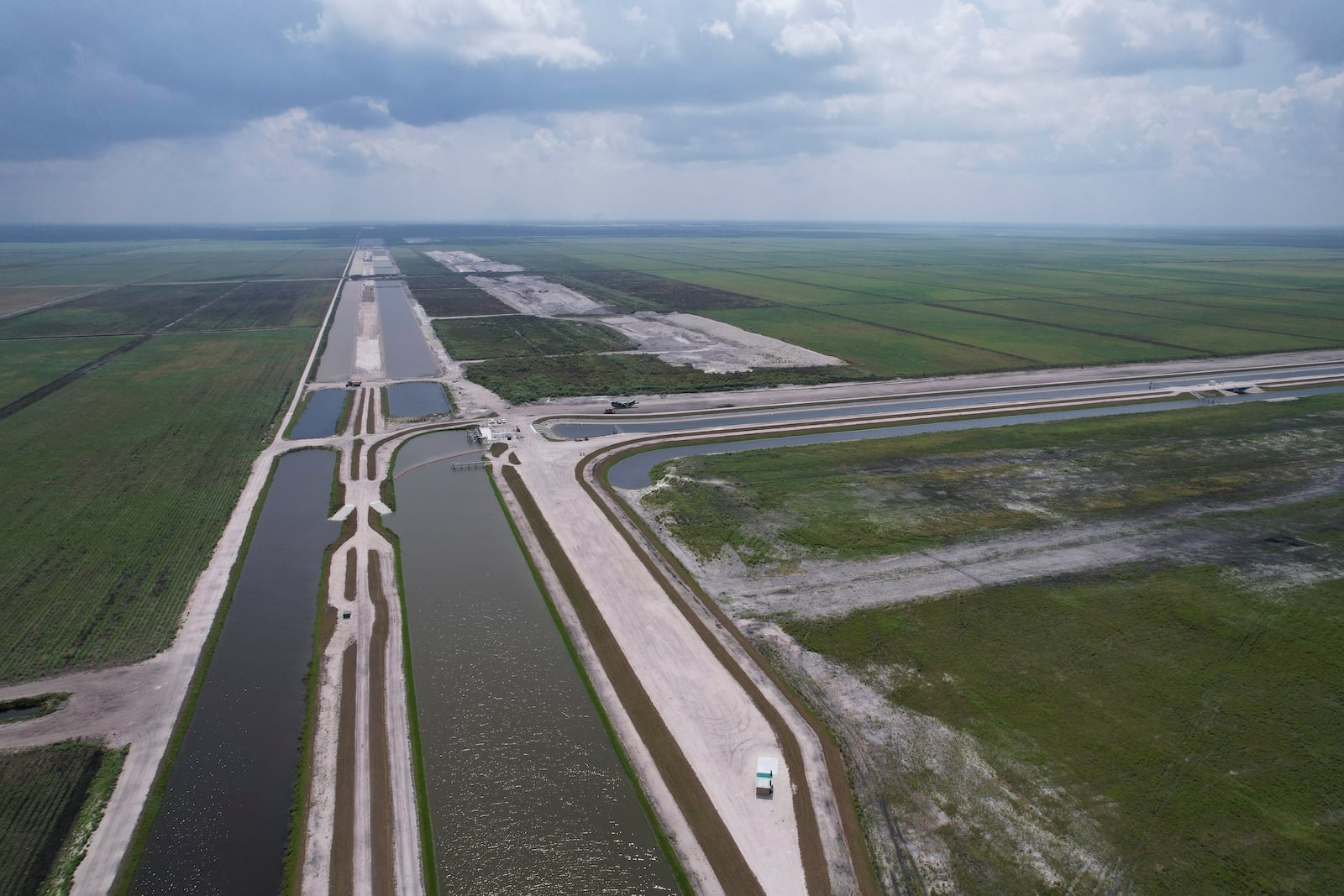 Canals run past the site, top right, where sugar cane fields are being converted into the Everglades Agricultural Area Reservoir, intended to store polluted water from Lake Okeechobee and agricultural runoff until it can be cleaned in a stormwater treatment area, bottom right, and released to flow south into the Everglades, Wednesday, May 15, 2024, in South Bay, Fla. (AP Photo/Rebecca Blackwell)