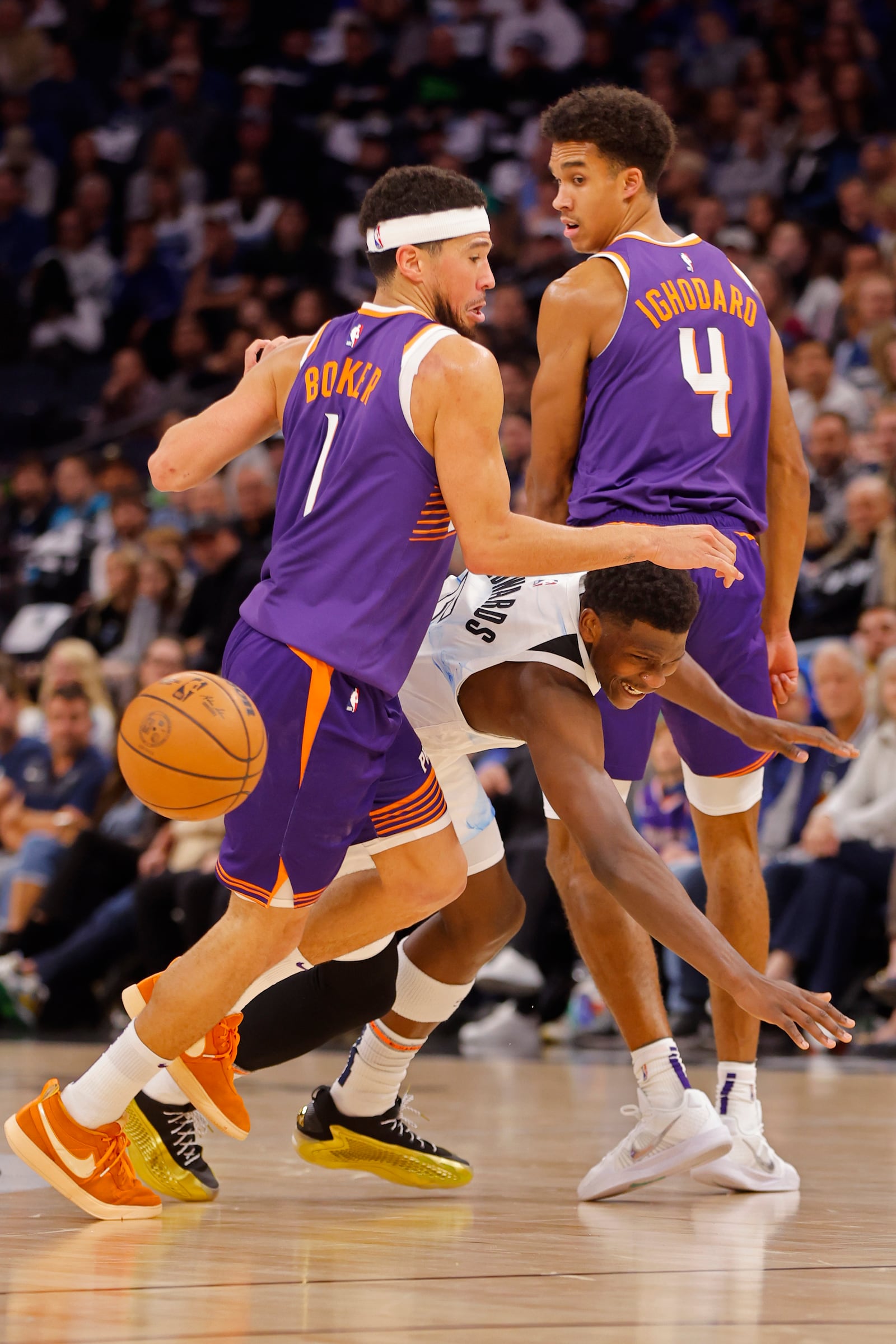 Phoenix Suns forward Oso Ighodaro (4) fouls Minnesota Timberwolves guard Anthony Edwards, center, as Suns guard Devin Booker (1) also defends in the first quarter of an NBA basketball game Sunday, Nov. 17, 2024, in Minneapolis. (AP Photo/Bruce Kluckhohn)