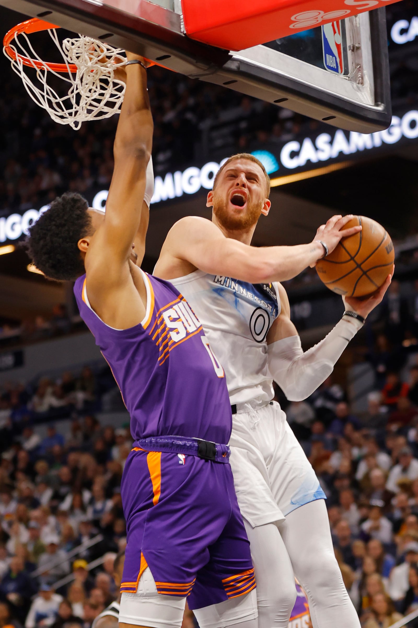 Minnesota Timberwolves guard Donte DiVincenzo (0) goes to the basket against as Phoenix Suns forward Royce O'Neale (0) defends him in the first quarter of an NBA basketball game, Sunday, Nov. 17, 2024, in Minneapolis. (AP Photo/Bruce Kluckhohn)