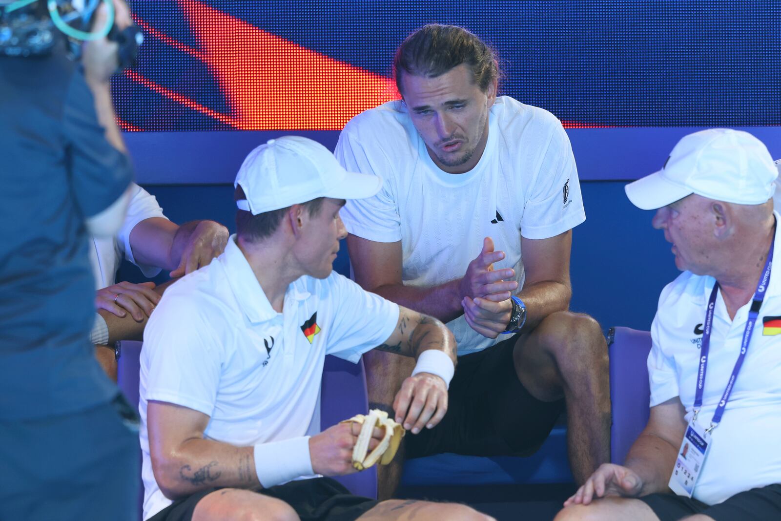 Alexander Zverev of Germany, center, talks to his replacement Daniel Masur, left, during a break in Germany's quarter final match against Alexander Shevchenko, after Zverev pulled out with a bicep injury from the United Cup tennis match in Perth, Australia, Wednesday, Jan. 1, 2025. (AP Photo/Trevor Collens)