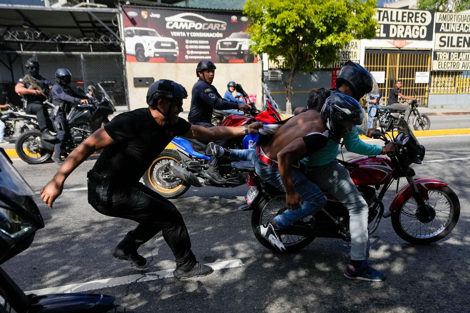 Police pursue opponents of Venezuelan President Nicolas Maduro, two people on the motorcycle at right, during a protest the day before Maduro's inauguration for a third term in Caracas, Venezuela, Thursday, Jan. 9, 2025. (AP Photo/Matias Delacroix)