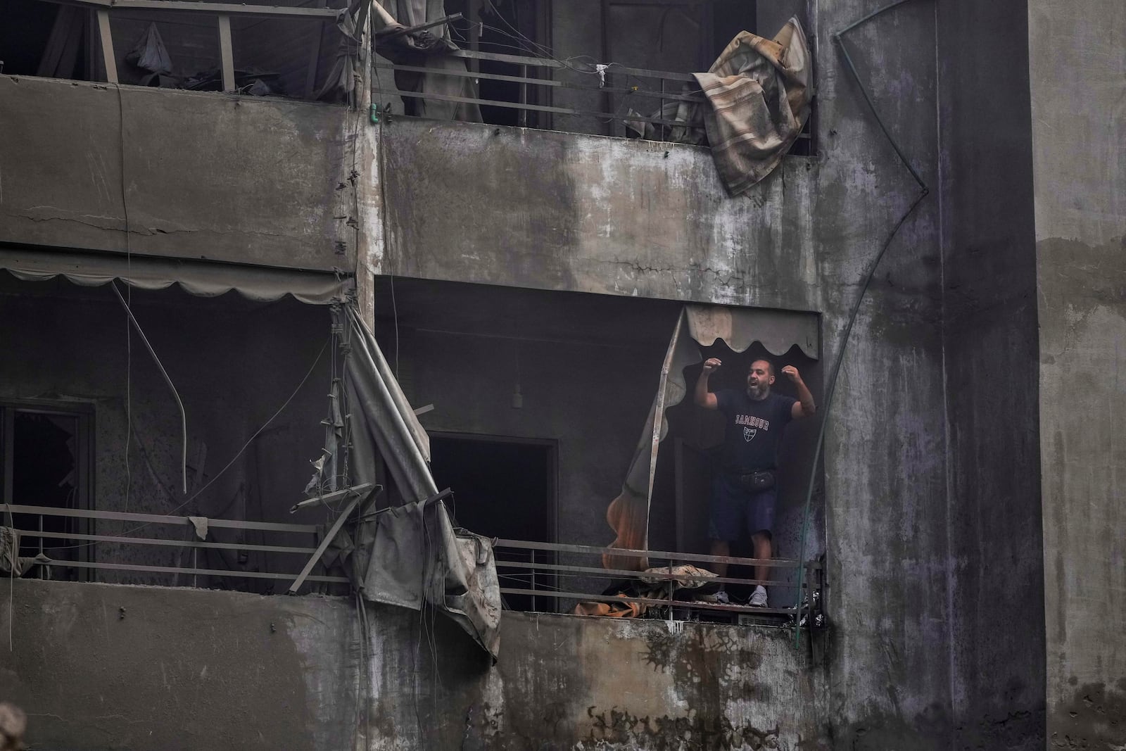 A man shouts slogans against Israel as he stands on the balcony of his damaged apartment at the site of an Israeli airstrike in Dahiyeh, Beirut, Lebanon, Friday, Nov. 1, 2024. (AP Photo/Hassan Ammar)