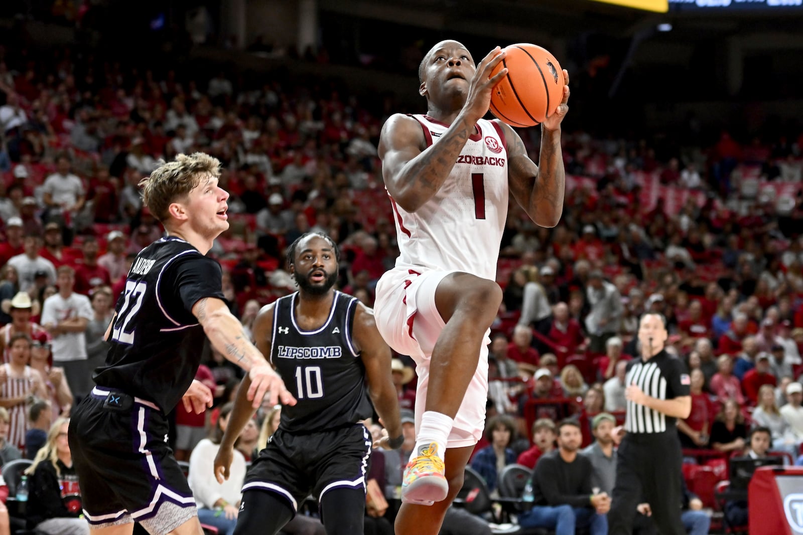 Arkansas guard Johnell Davis (1) drives past Lipscomb defenders Joe Anderson (22) and Gyasi Powell (10) during the second half of an NCAA college basketball game Wednesday, Nov. 6, 2024, in Fayetteville, Ark. (AP Photo/Michael Woods)