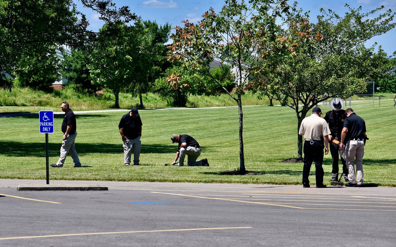 Butler County Sheriff’s detectives search Liberty Park of shell casings on Thursday afternoon. One man was killed and two others injured during shooting at the park Wednesday night. NICK GRAHAM/STAFF