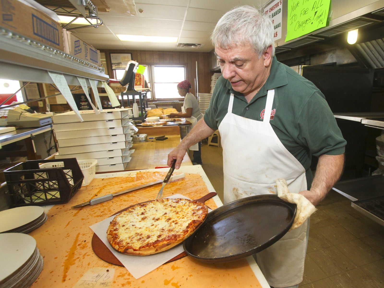 Nick Dadabo, one of the owners of Hamilton’s Chester Pizza, gets a pie out the oven, Tuesday, April 1, 2014, a day which marks Chester’s 60th anniversary. GREG LYNCH / STAFF