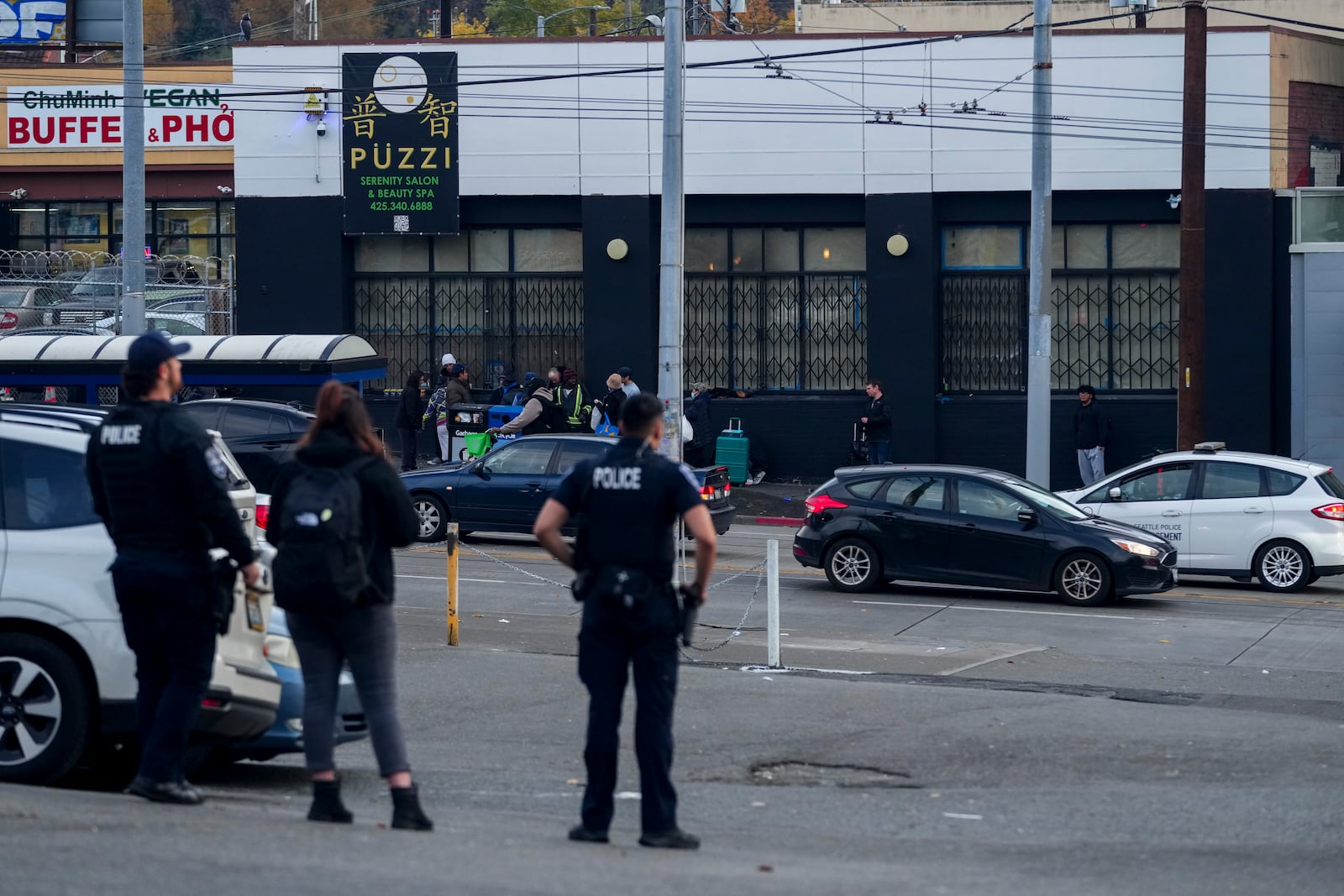 Police officers stand near the scene as they gather security camera footage after multiple people were stabbed Friday, Nov. 8, 2024, in the Chinatown-International District in Seattle. (AP Photo/Lindsey Wasson)