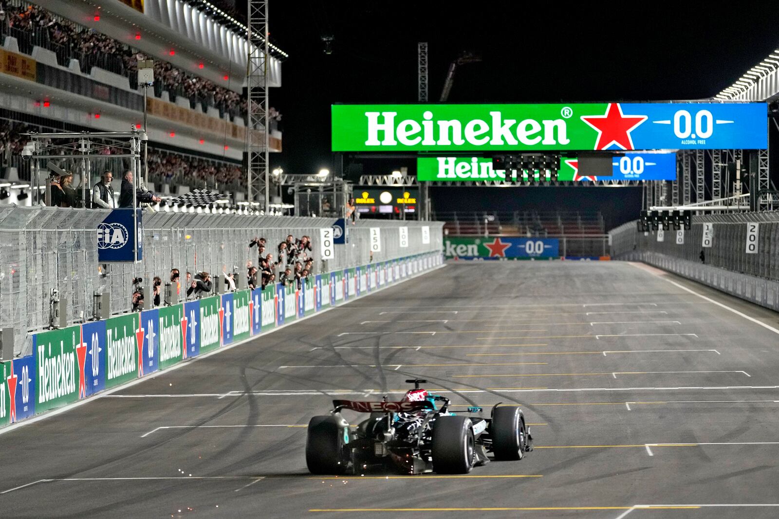 Actor Sylvester Stallone, left, waves the checkered flag as Mercedes driver George Russell, of Britain, crosses the finish line during the Formula One U.S. Grand Prix auto race, Saturday, Nov. 23, 2024, in Las Vegas. (AP Photo/Matt York)