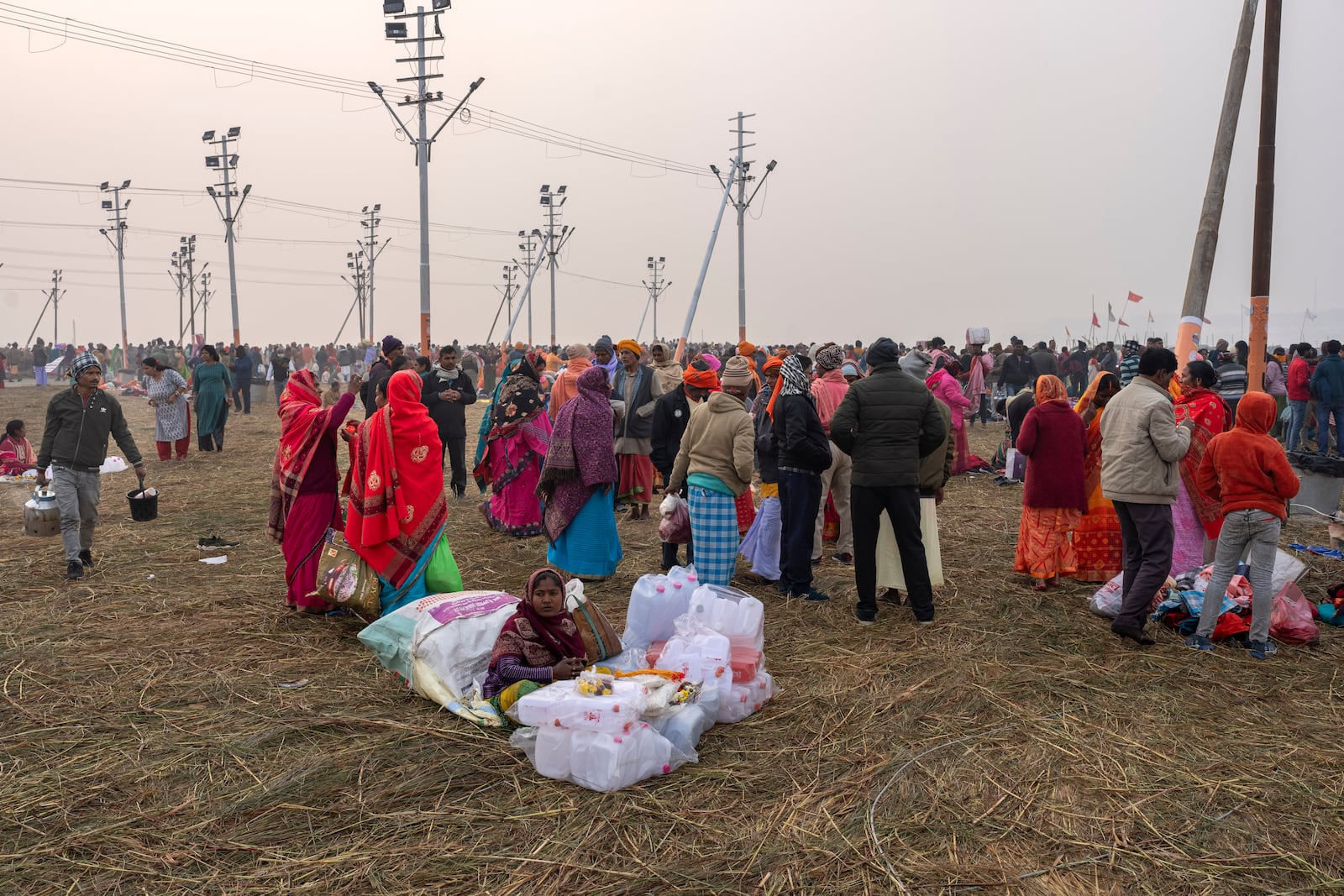 A woman sells empty plastic containers as devotees arrive to bathe at the confluence of the Ganges, the Yamuna and the mythical Saraswati rivers, a day before the official beginning of the 45-day-long Maha Kumbh festival, in Prayagraj, India, Sunday, Jan. 12, 2025. (AP Photo/Ashwini Bhatia)