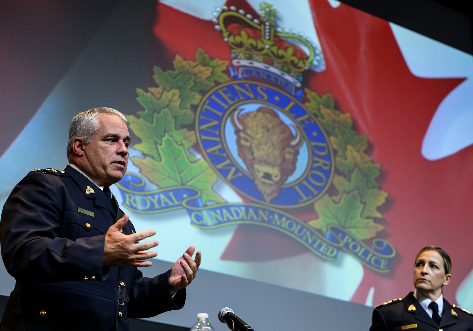 RCMP Commissioner Mike Duheme, left, speaks to a journalist as he concludes a news conference with Assistant Commissioner Brigitte Gauvin, right, at RCMP National Headquarters in Ottawa, Ontaio, Monday, Oct. 14, 2024. (Justin Tang/The Canadian Press via AP)