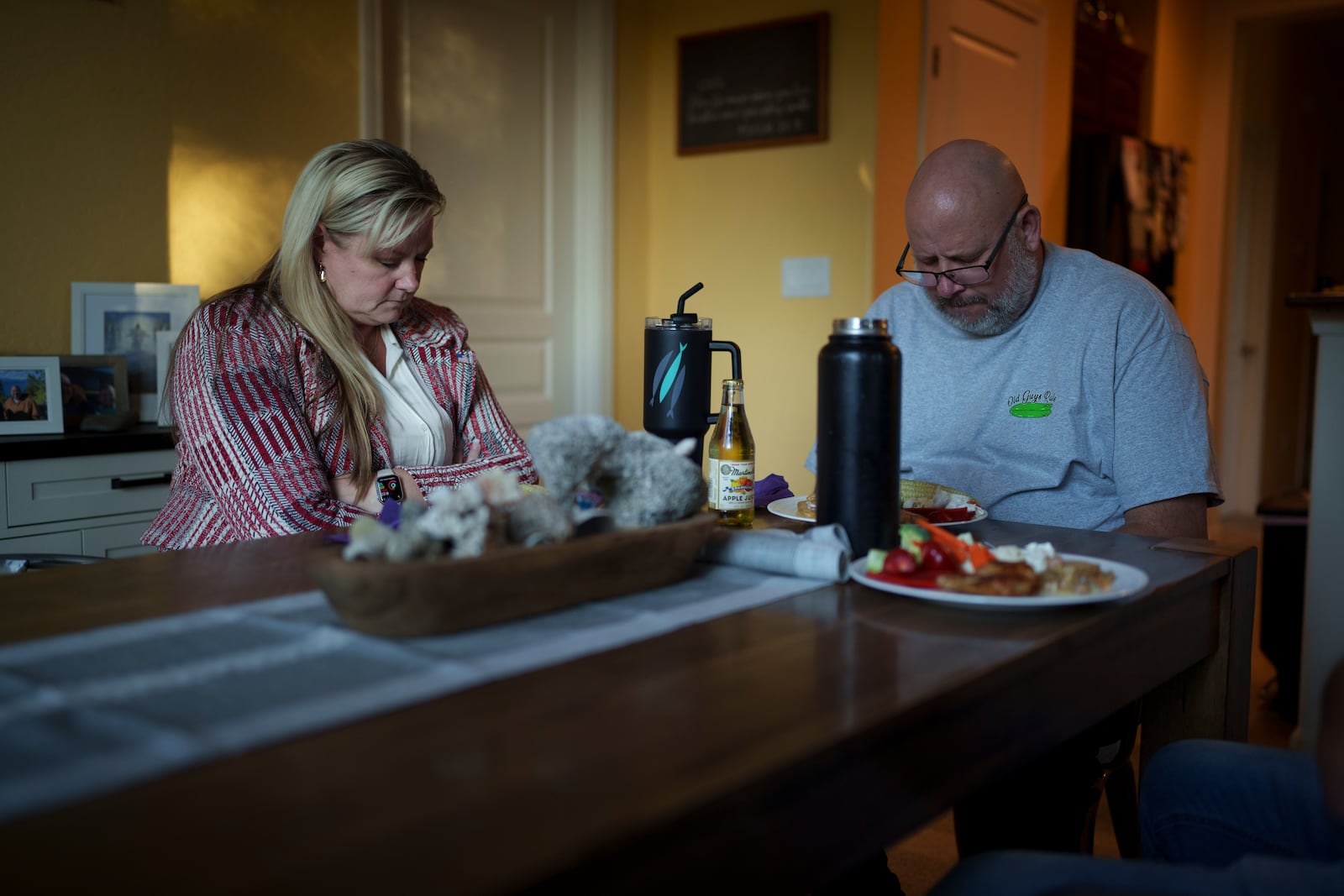 Cari-Ann Burgess, interim Registrar of Voters for Washoe County, Nev., left, prays with her husband Shane Burgess before eating dinner at their home Friday, Sept. 20, 2024, in Reno, Nev. (AP Photo/John Locher)