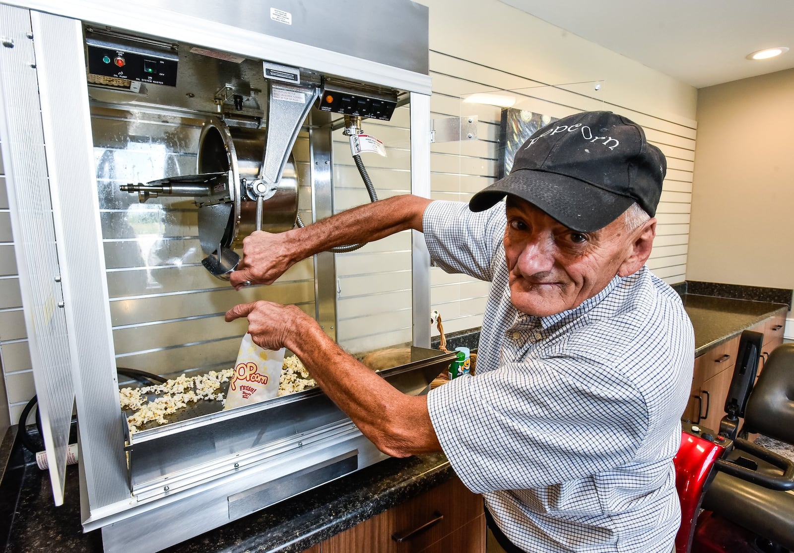 Lynn “Popcorn” Weber serves popcorn from the machine near the movie theater at Otterbein SeniorLife Wednesday, July 18. Weber has come full circle from when he was a resident of the Otterbein Children’s Home when he was a child. Weber came to the Children’s home in 1959 and stayed for four years before he was moved to another home in northern Ohio. He is now back at Otterbein as a resident. His nickname, Popcorn, was given to him in high school when he ran the concession stand for sporting events and has stuck with him. NICK GRAHAM/STAFF