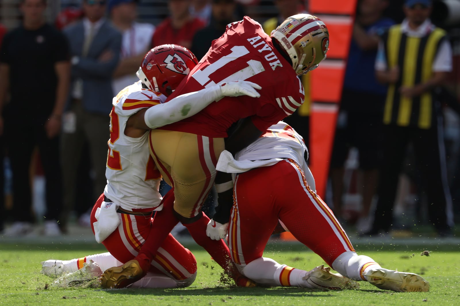 San Francisco 49ers wide receiver Brandon Aiyuk (11) is hit by Kansas City Chiefs cornerback Trent McDuffie, left, and safety Chamarri Conner during the first half of an NFL football game in Santa Clara, Calif., Sunday, Oct. 20, 2024. (AP Photo/Jed Jacobsohn)