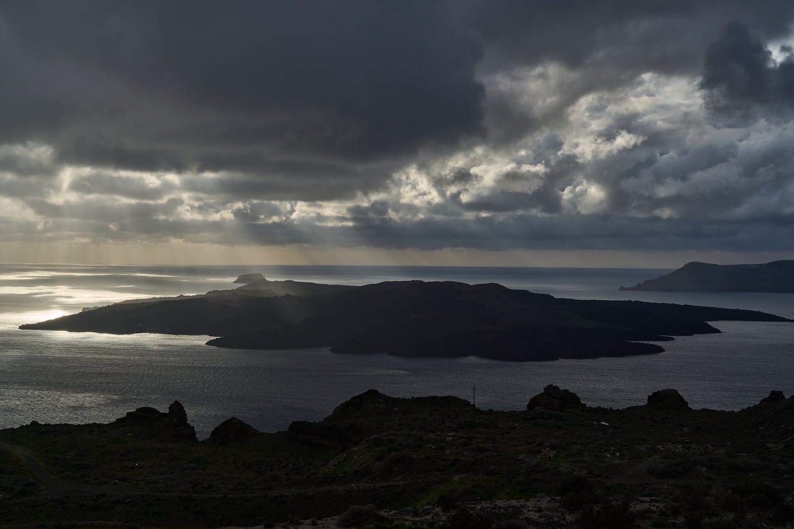 Sun rays illuminate the volcanic islet of Nea Kameni, part of the earthquake-struck island of Santorini, Greece, Tuesday, Feb. 4, 2025. (AP Photo/Petros Giannakouris)