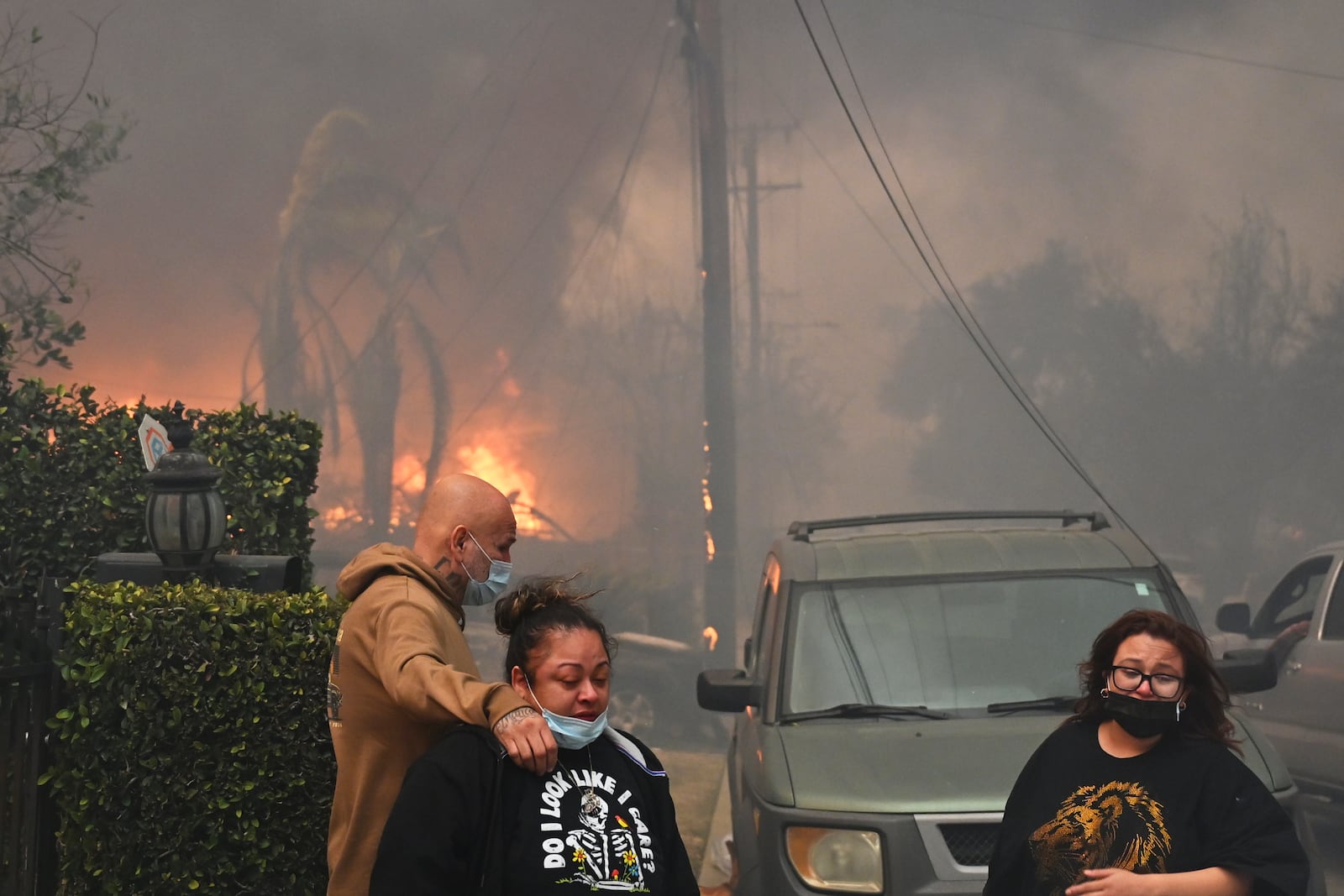 Residents embrace in front of burning structures as the Eaton Fire advances Wednesday, Jan. 8, 2025 in Altadena, Calif. (AP Photo/Nic Coury)