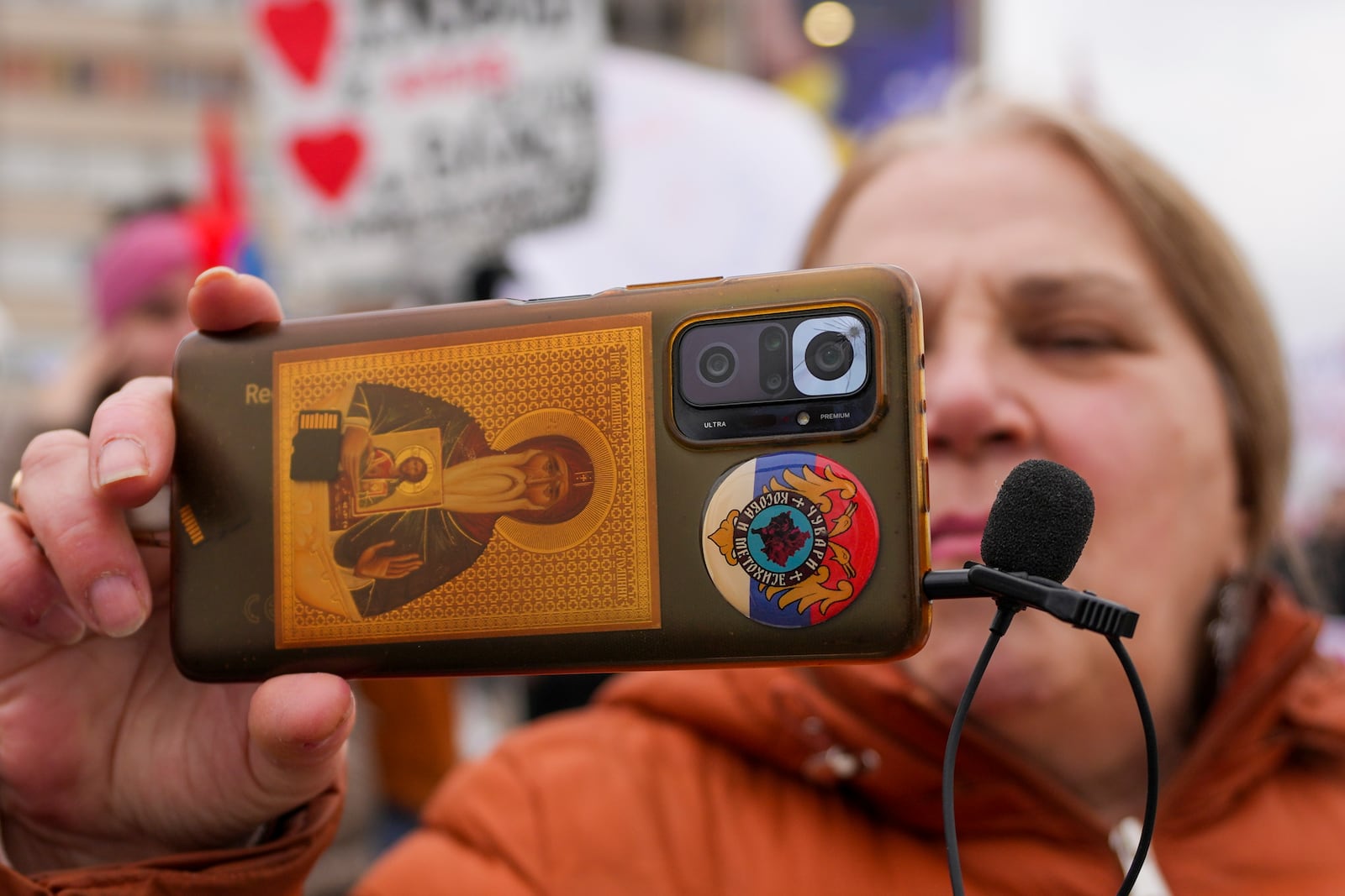 A woman records video with her smartphone during a protest triggered after a concrete canopy on a railway station in the northern city of Novi Sad collapsed on Nov. 1, 2024 killed 15 people, in Kragujevac, Serbia, Saturday, Feb. 15, 2025. (AP Photo/Darko Vojinovic)