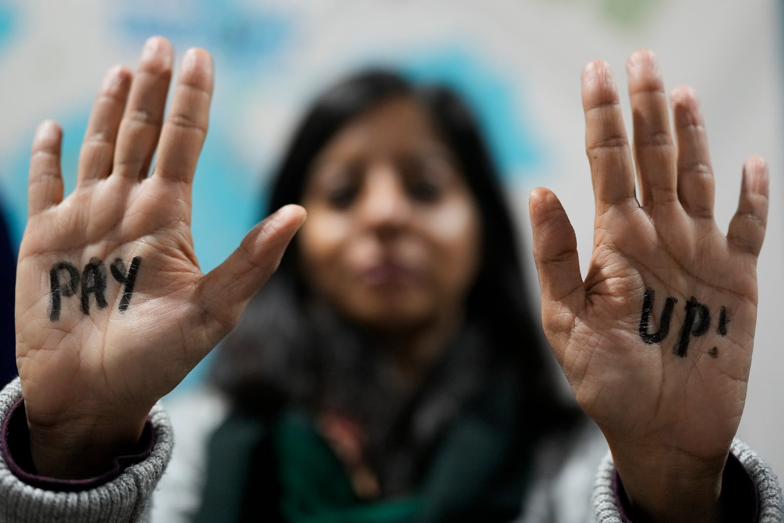 FILE - A demonstrator displays hands that read "pay up" during a protest for climate finance at the COP29 U.N. Climate Summit, Nov. 23, 2024, in Baku, Azerbaijan. (AP Photo/Rafiq Maqbool, File)