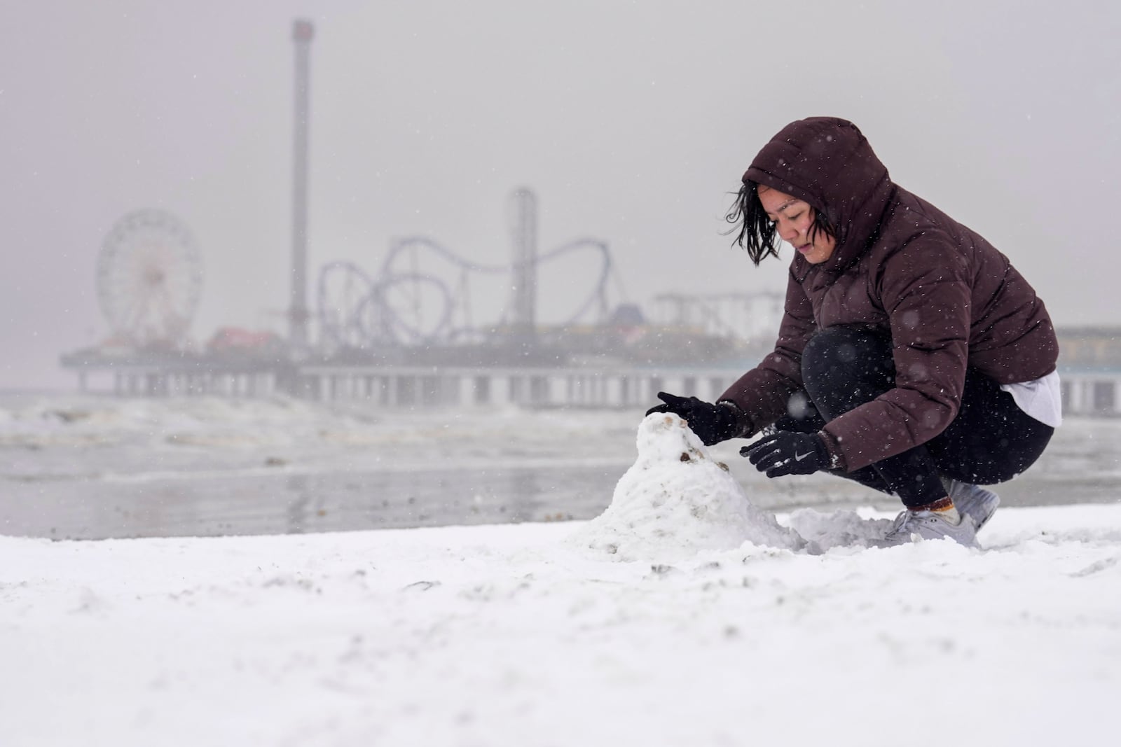 Paige Encarnacion builds a snowman on the beach during a winter storm on Tuesday, Jan. 21, 2025 in Galveston, Texas. (Brett Coomer/Houston Chronicle via AP)