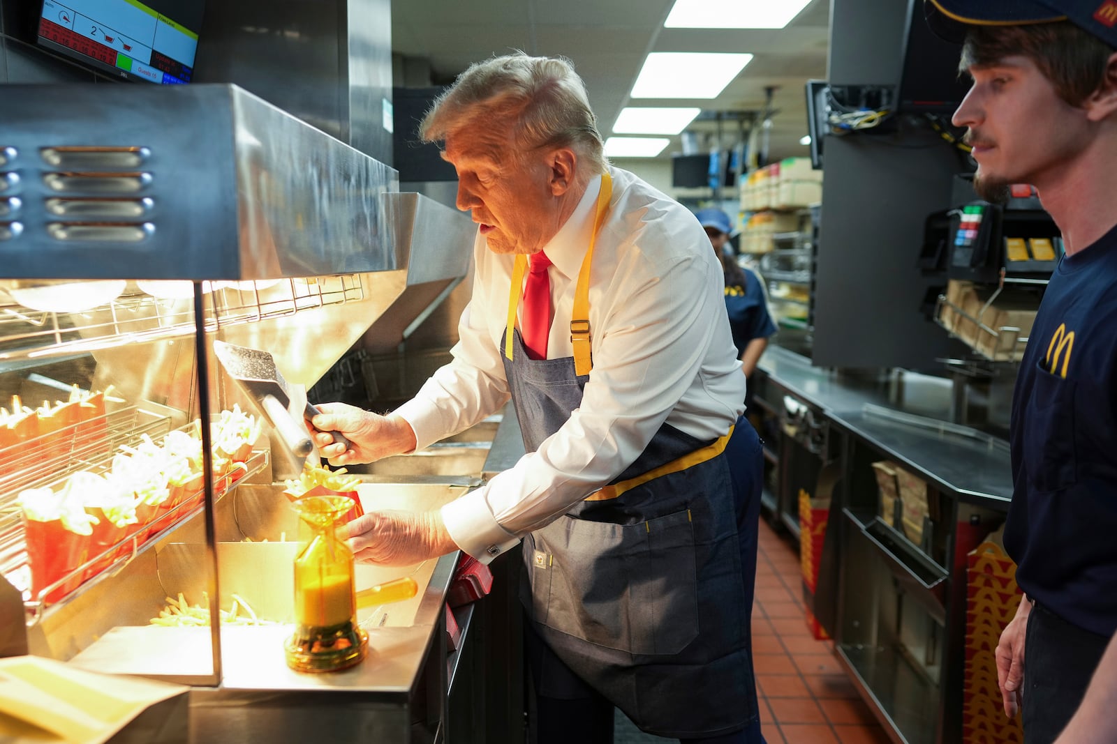 Republican presidential nominee former President Donald Trump serves french fries as an employee looks on during a visit to McDonald's in Feasterville-Trevose, Pa., Sunday, Oct. 20, 2024. (Doug Mills/The New York Times via AP, Pool)