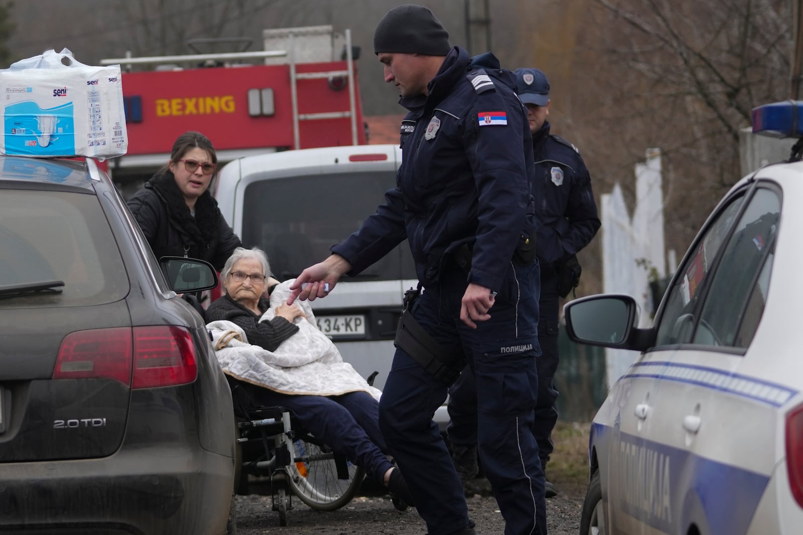 People evacuate people in front of a home for the elderly where eight people died in a fire, in Barajevo, a municipality of Belgrade, Serbia, Monday, Jan. 20, 2025. (AP Photo/Darko Vojinovic)