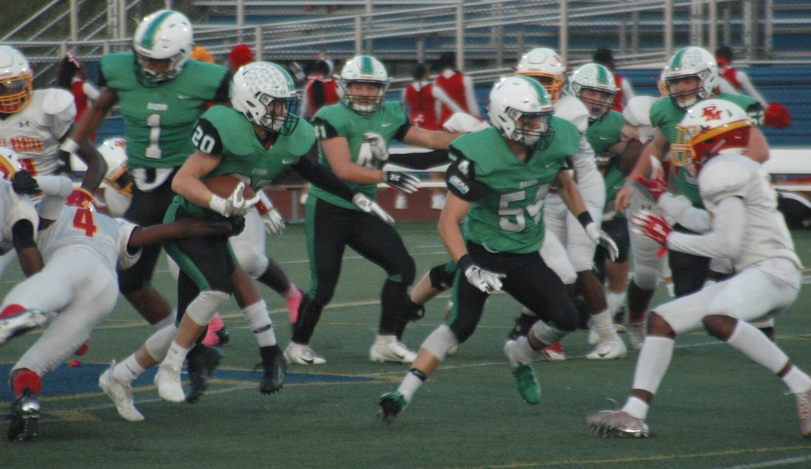 Badin’s Alex DeLong (20) breaks through a tackle attempt by Purcell Marian’s Jaylen Hines (4) during Saturday night’s game at Monroe. That’s Evan Schlensker (54) doing some blocking up front for the Rams in their 24-7 triumph. RICK CASSANO/STAFF