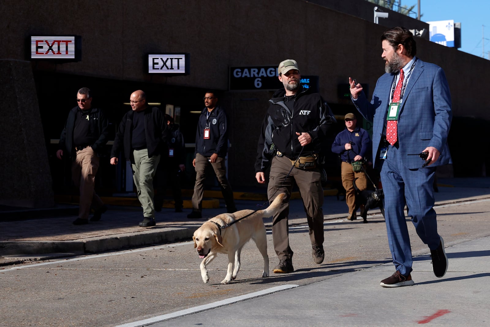 Security with bomb sniffing dogs patrol the area around the Superdome ahead of the Sugar Bowl NCAA College Football Playoff game, Thursday, Jan. 2, 2025, in New Orleans. (AP Photo/Butch Dill)