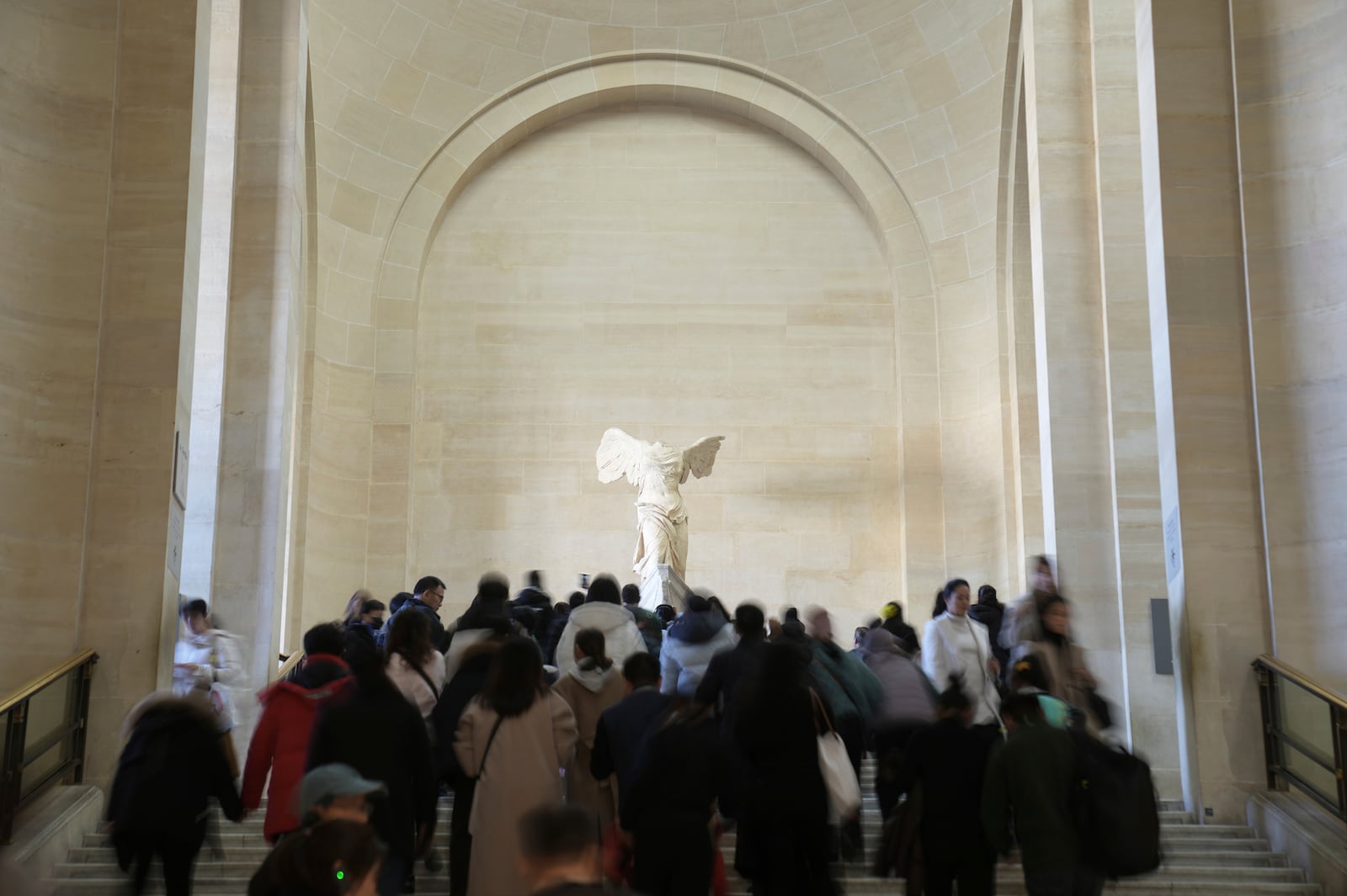 Visitors climb up stairs to watch the marble hellenic sculpture The Winged Victory of Samothrace in Le Louvre museum, Monday, Jan. 27, 2025 in Paris. (AP Photo/Thibault Camus)