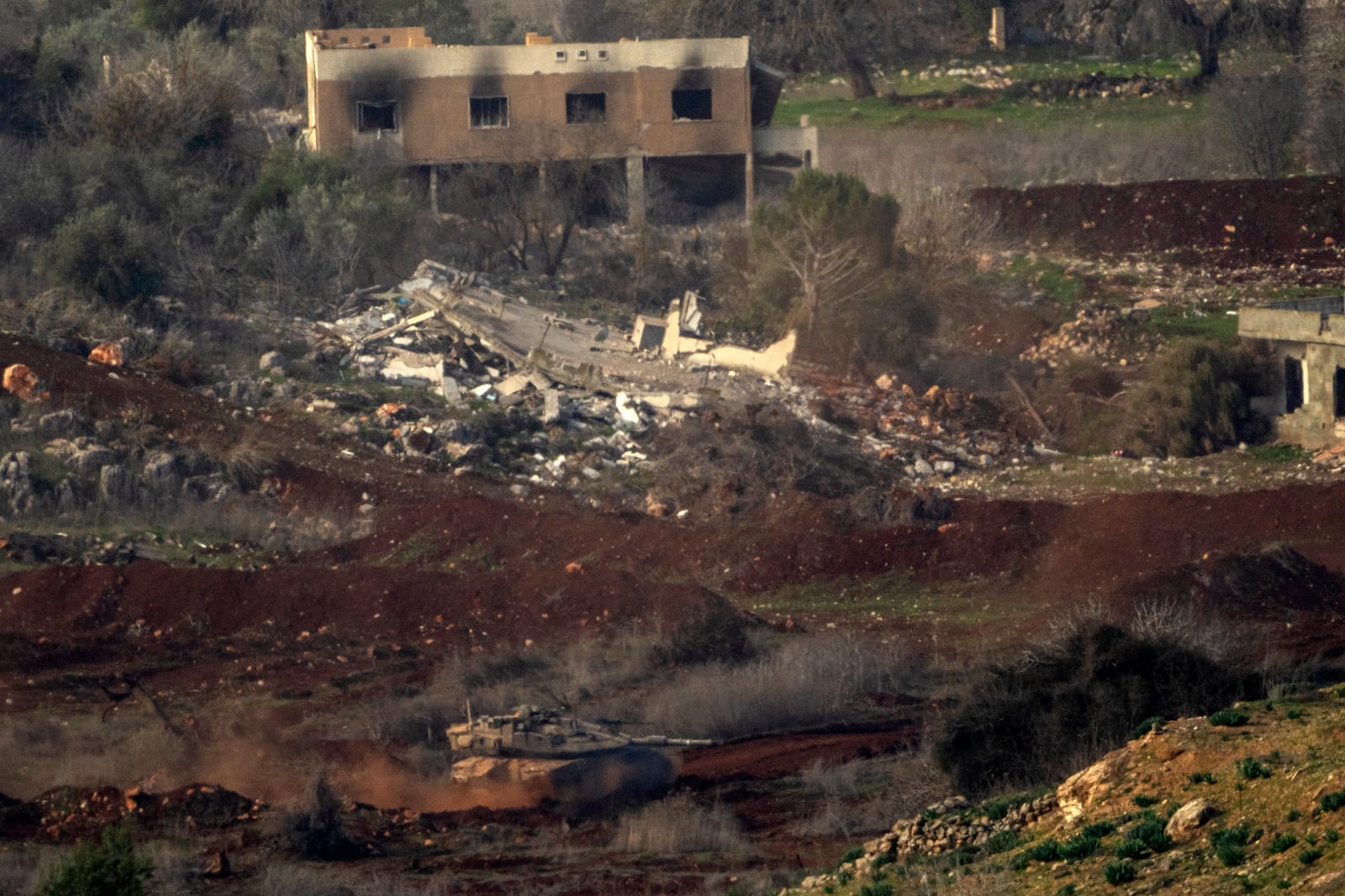 An Israeli tank maneuvers inside a village in southern Lebanon, as seen from northern Israel, Thursday, Jan. 23, 2025. (AP Photo/Ariel Schalit)